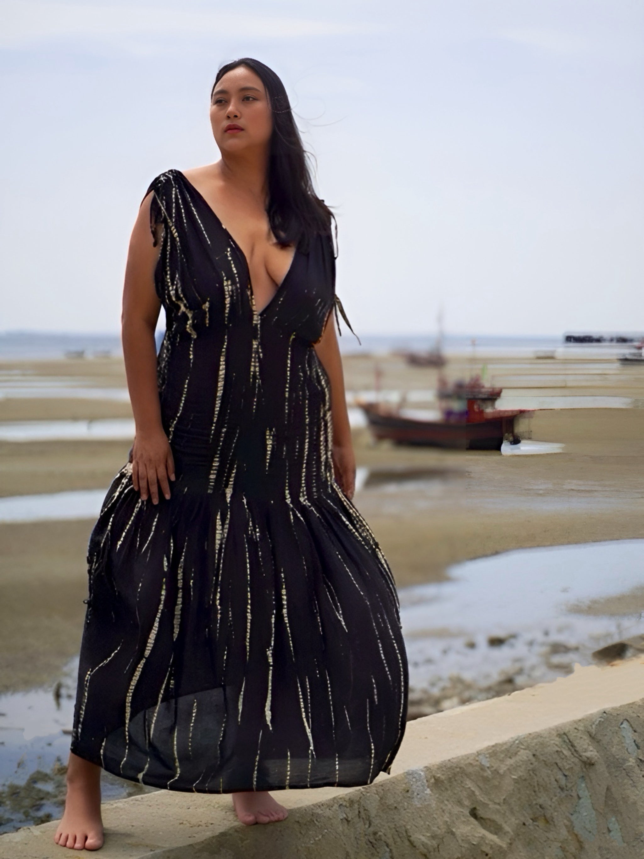 Model wearing a flowy, black tie-dye goddess kaftan dress with deep V-neckline and ruffled hem, handcrafted from soft rayon. Oversized boho kaftan designed for beachwear, resort lounging, or stylish everyday wear.