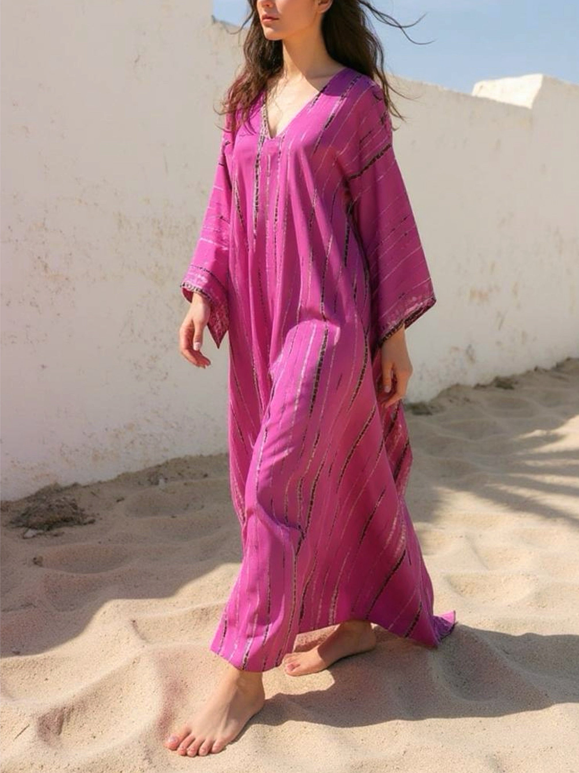 Woman wearing a handmade tie dye pink dress standing against a white wall with shadows, boho look