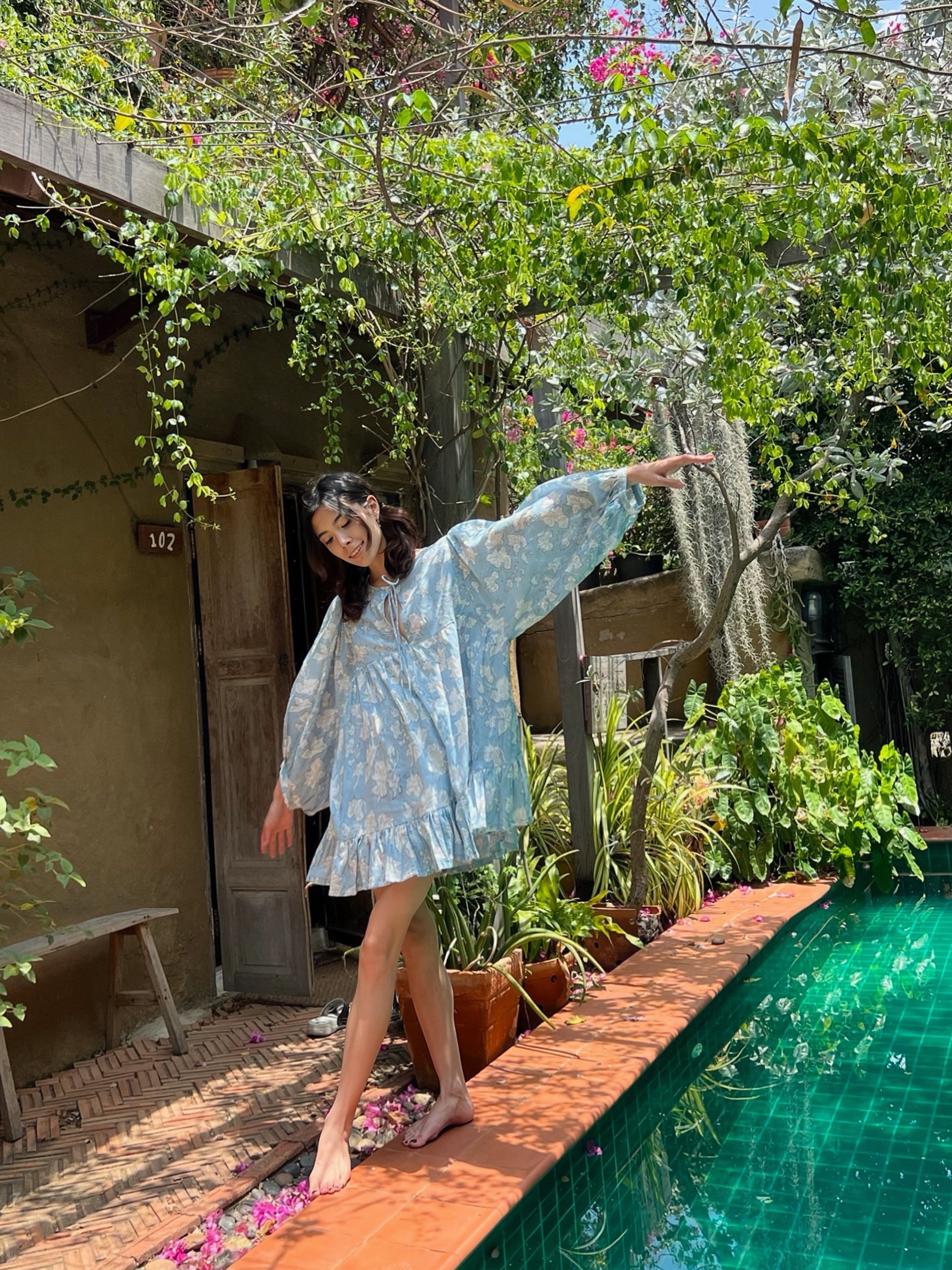 Shop Coco de Chom Lola Bohemian Mini Dress in Beautiful Blue Sky - A Truly Unique Limited Edition Piece. Handcrafted with Wooden Blocks on Fine Cotton Voile, Showcasing a Dreamy Block Printed Pattern Inspired by Bougainvillea Flowers and Vacations. Ideal for Beach Days, Vacations, and Boho Enthusiasts.