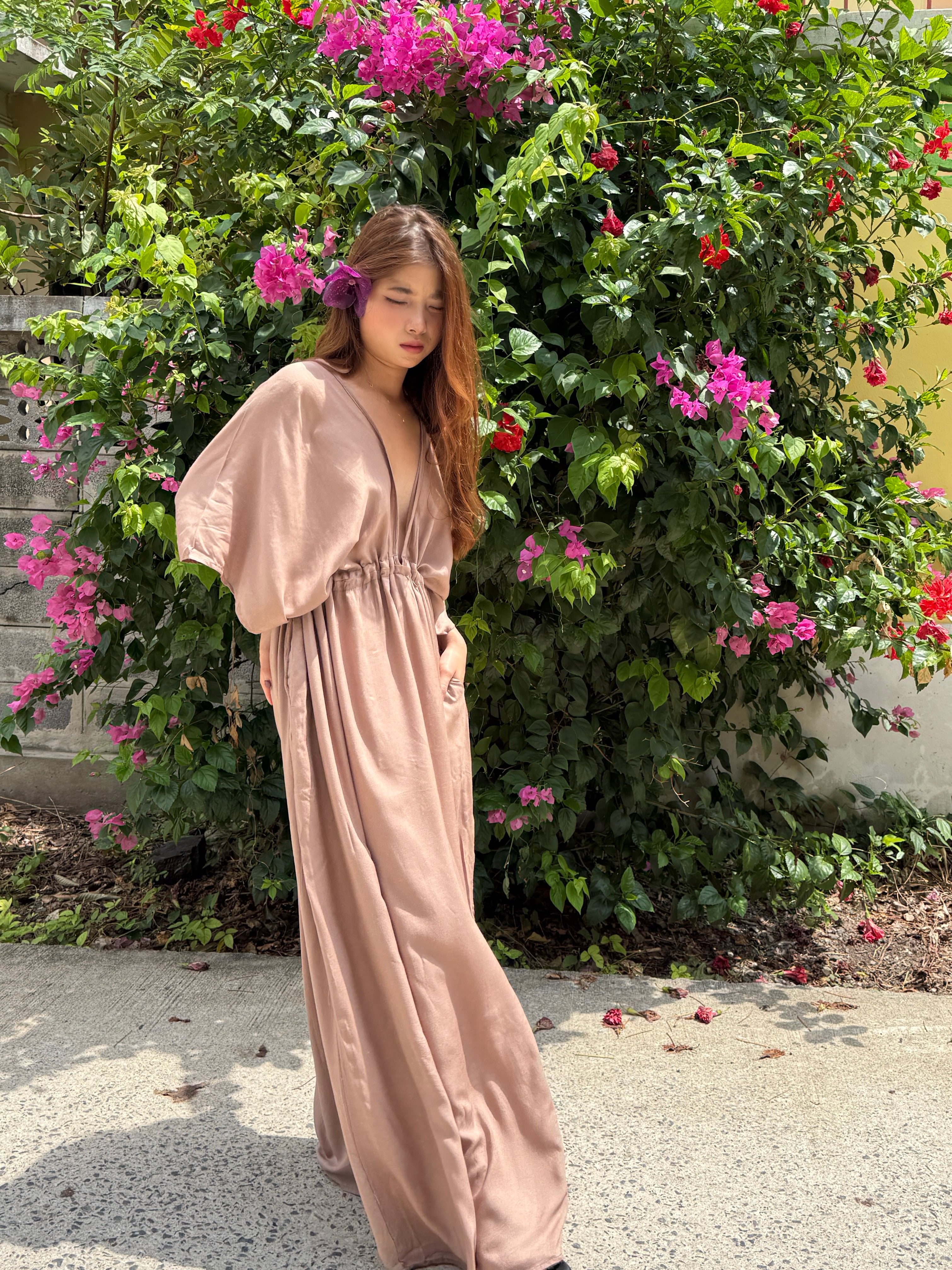 long kaftan dress in nude worn by the resort style, oversized beach cover up and plus size friendly resort maxi dress with deep V neckline, side slit, and flowy silhouette