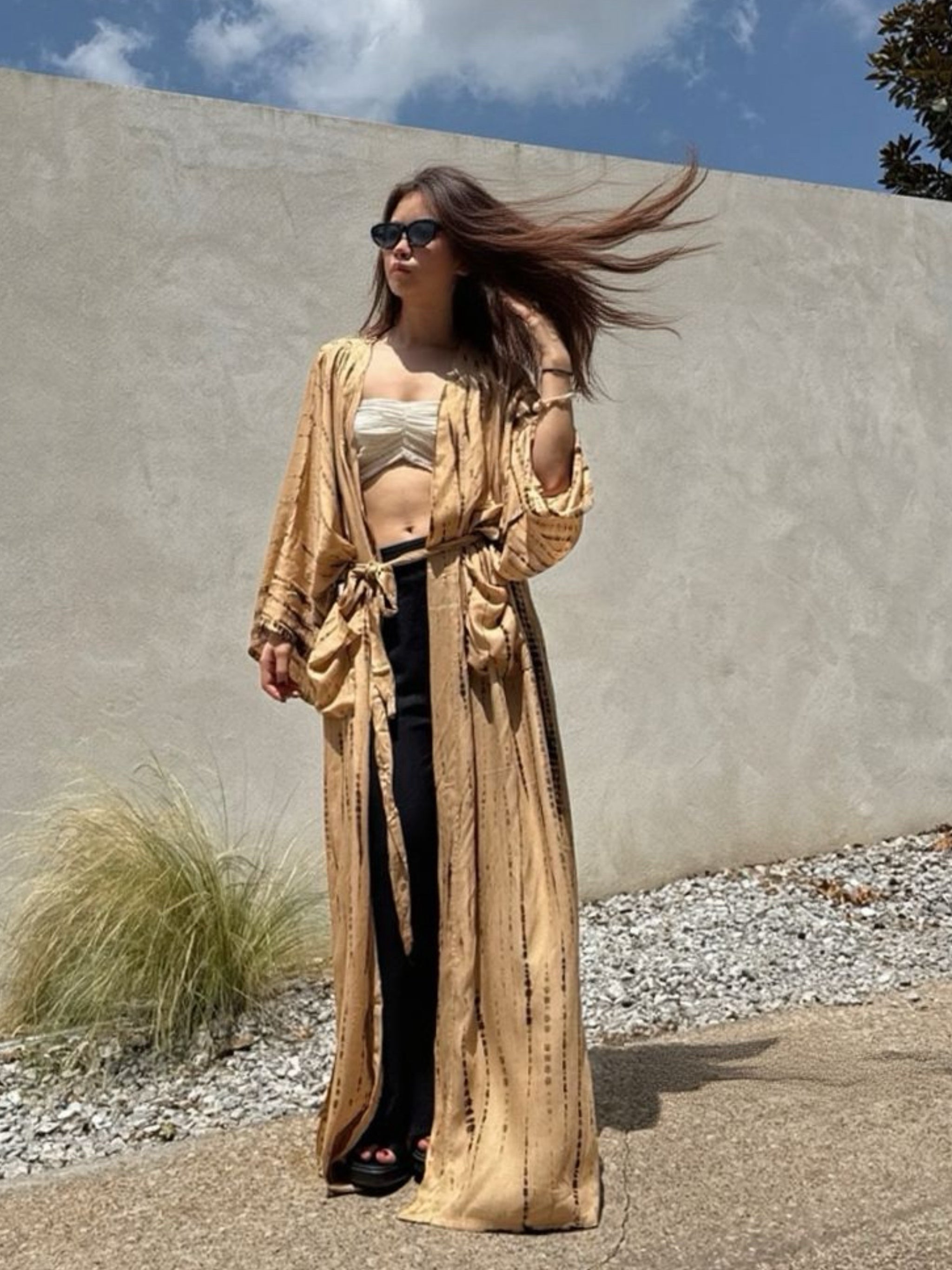 Woman wearing a tan tie-dye long kimono robe from Coco de Chom. The oversized robe features long sleeves, a waist tie, and a relaxed, boho-style fit.
