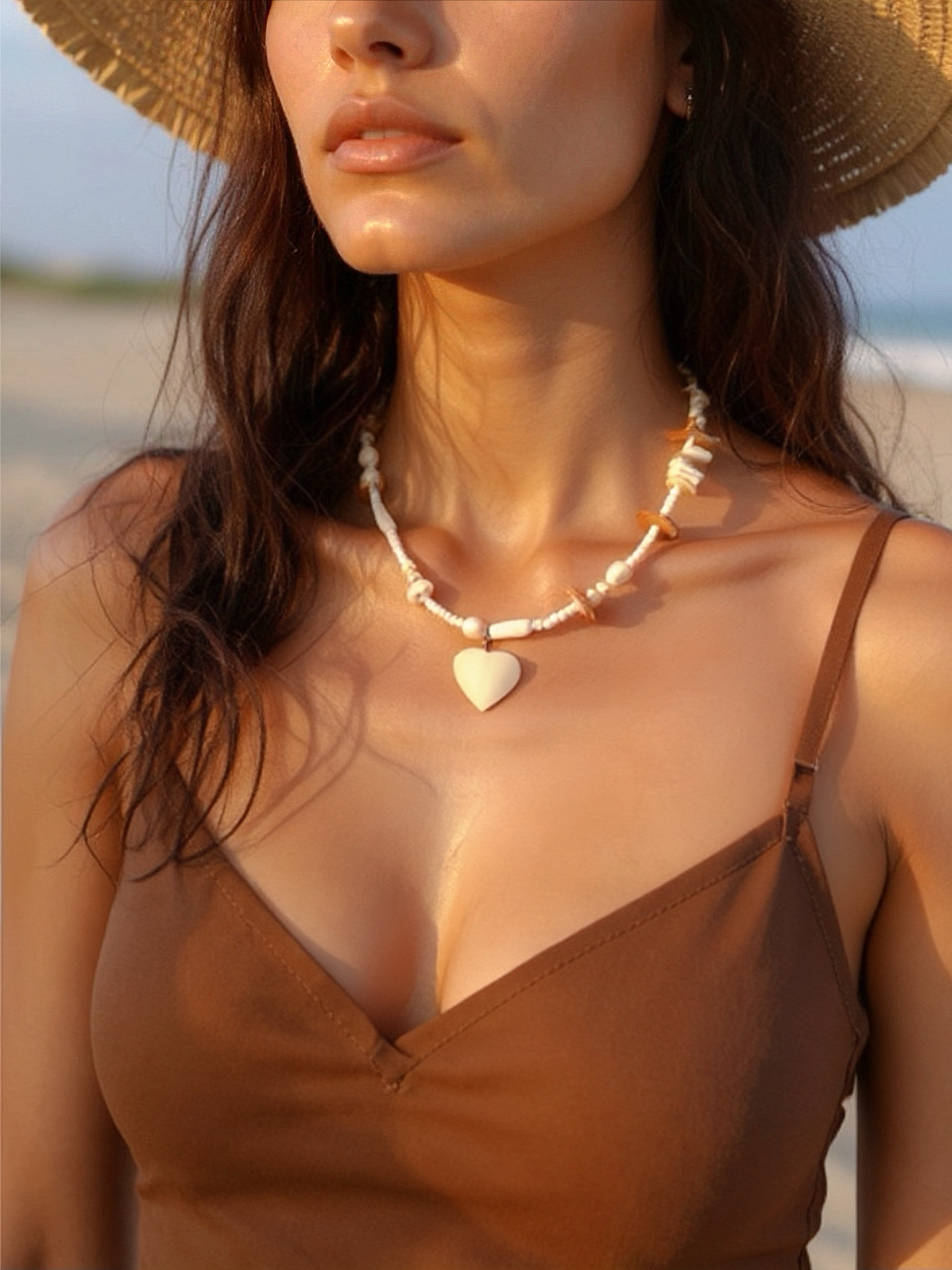 Woman wearing Ocean Heart shell necklace by the ocean, styled for a coastal summer wedding or beach vacation.
