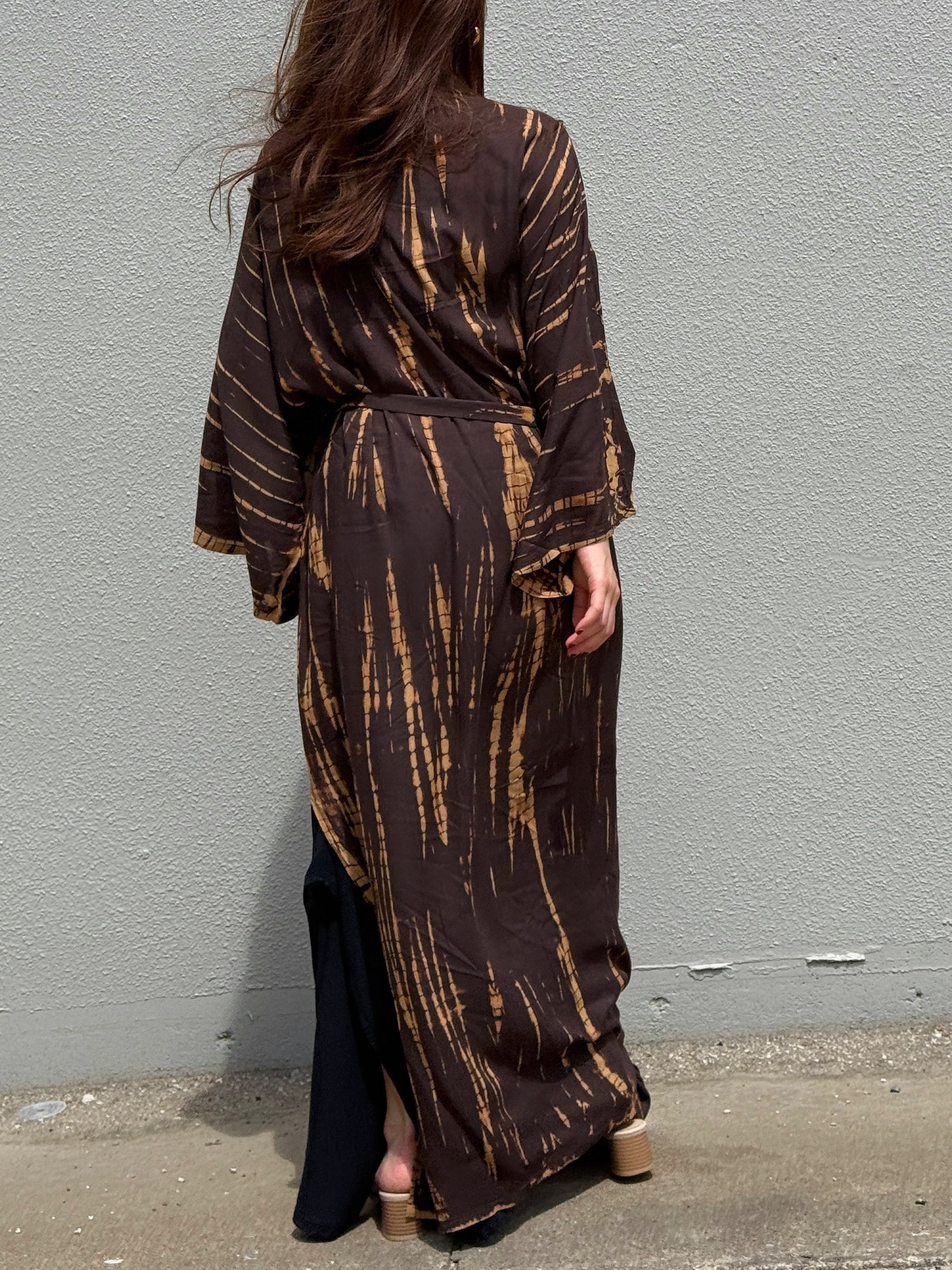 Woman wearing a handmade long tie-dye kimono robe in brown with long sleeves and adjustable waist tie, styled as a boho duster and lightweight beach cover-up by Coco de Chom.