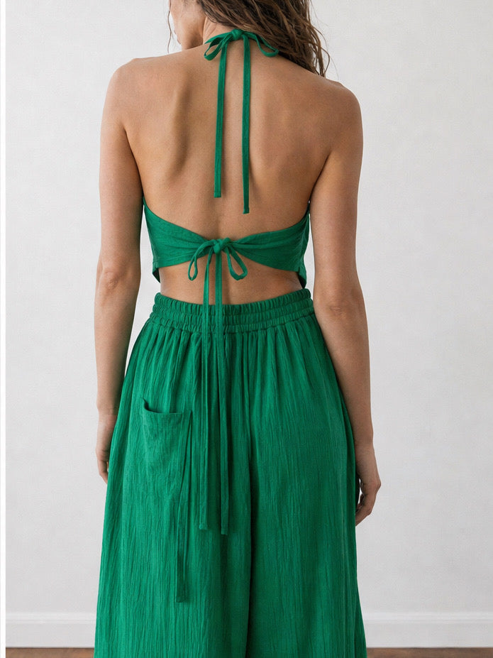 Woman wearing an emerald green handkerchief halter top and matching wide leg pants, boho vacation outfit and resort wear set for beach travel