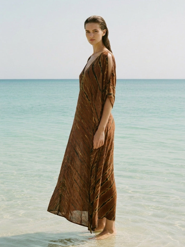 Woman wearing a brown zebra tie dye V neck kaftan dress with oversized flowy silhouette and cold shoulder detail