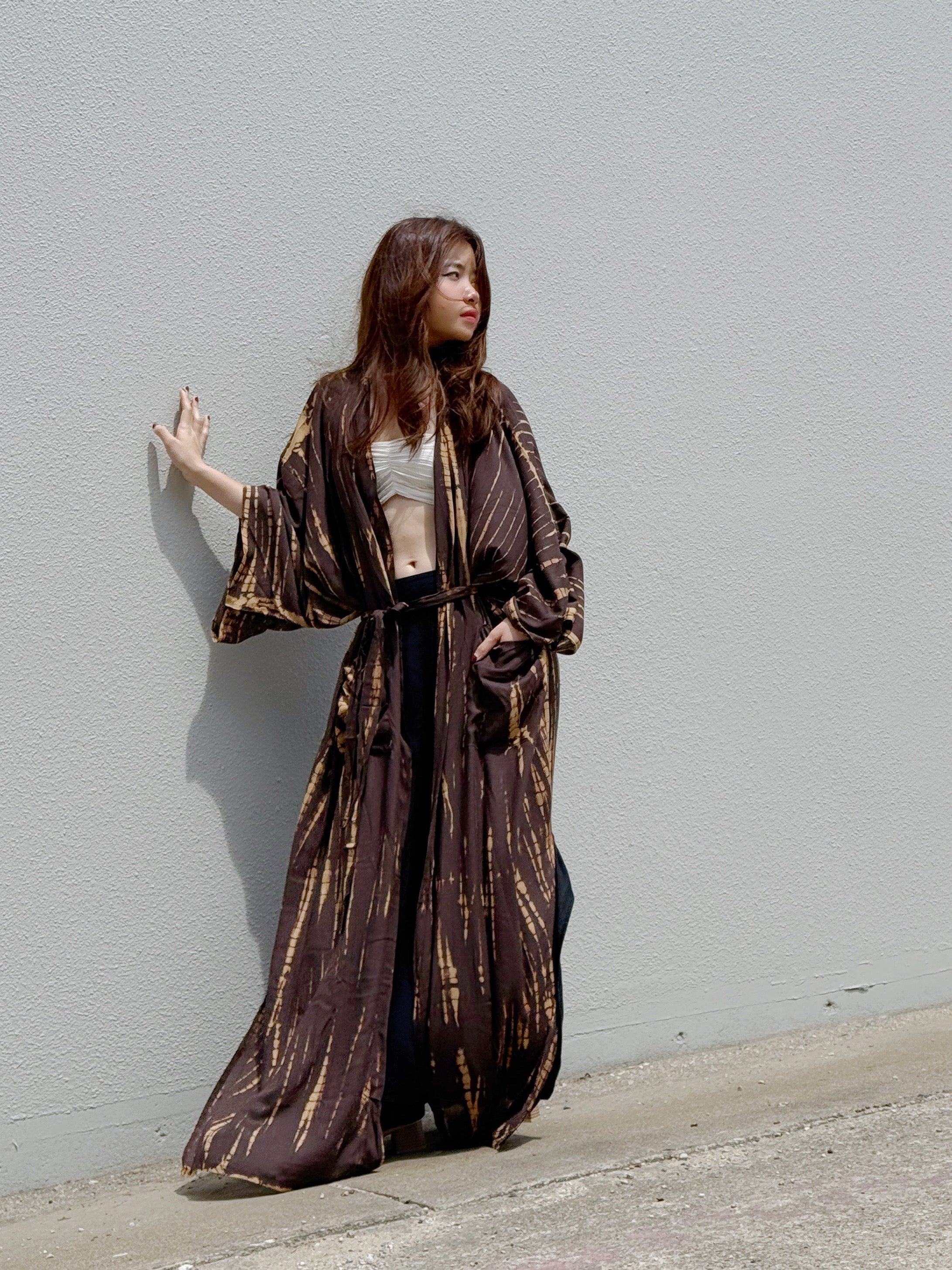 Woman wearing a handmade brown tie-dye kimono robe with long sleeves and adjustable waist tie, styled as a boho duster and lightweight beach cover-up by Coco de Chom.