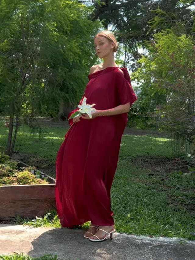 Woman wearing the Helena Red Burgundy Kaftan by Coco De Chom — an elegant off-shoulder satin resort dress with a free-flowing silhouette, tie details, and silky eco-friendly fabric. Perfect for beach vacations, resort wear, or effortless boho luxury