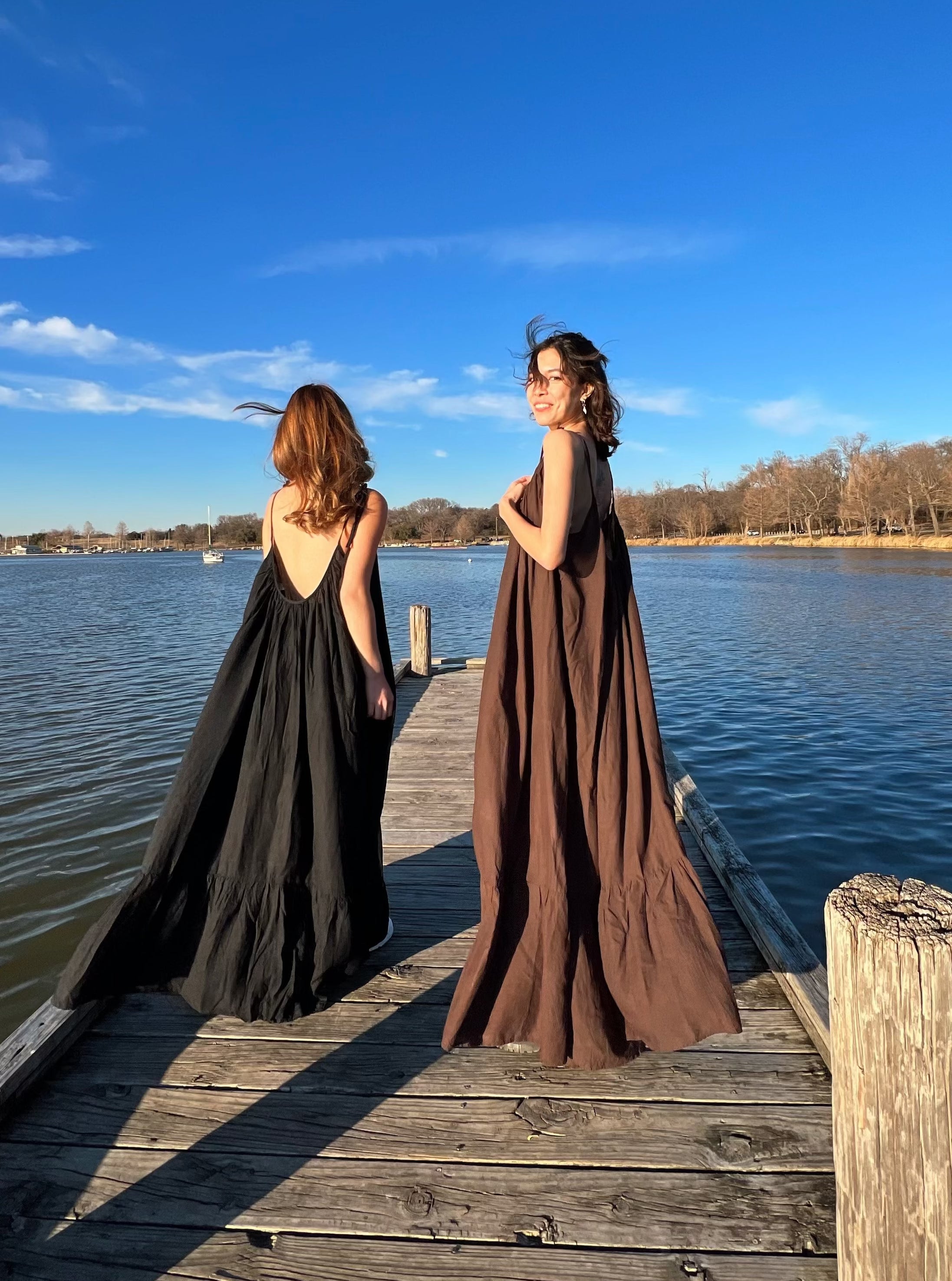 Women in a hand-dyed black backless maxi dress standing by the sea, boho vacation style, wearing boho resortwear by Coco de Chom