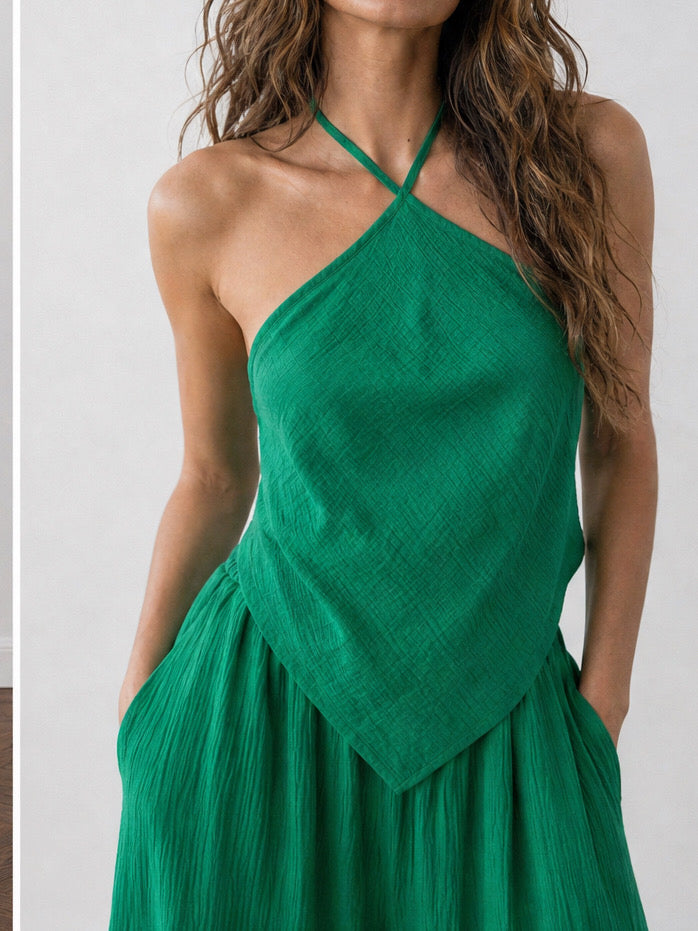 Woman wearing an emerald green handkerchief halter top and matching wide leg pants, boho vacation outfit and resort wear set for beach travel