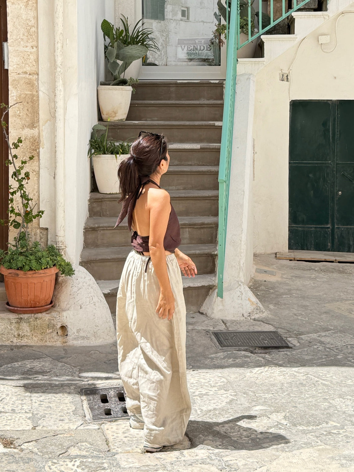 Woman wearing barrel cut linen pants on beach vacation – lightweight wide-leg trousers styled for effortless travel and summer comfort