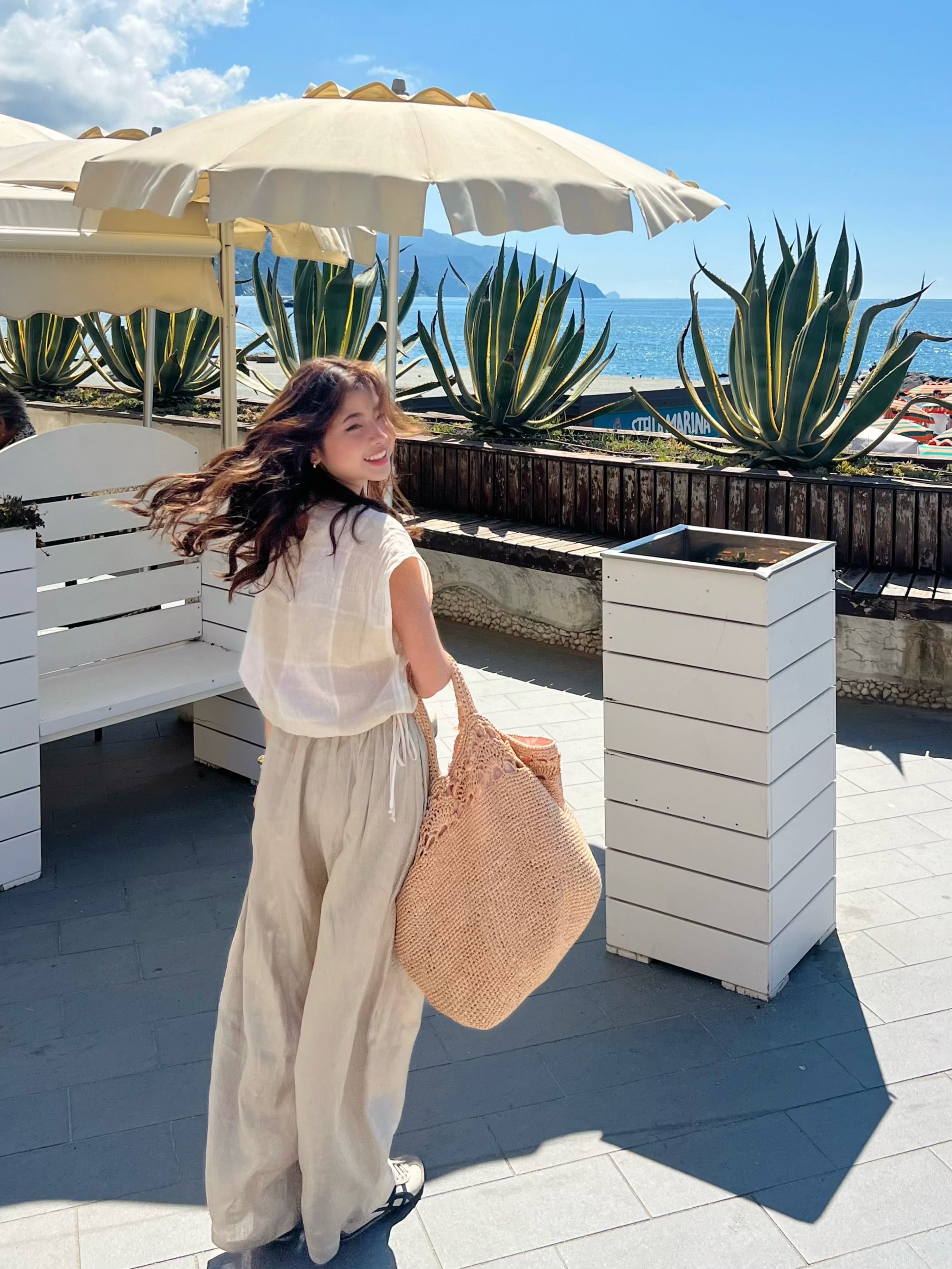 Woman wearing barrel cut linen pants on beach vacation – lightweight wide-leg trousers styled for effortless travel and summer comfort
