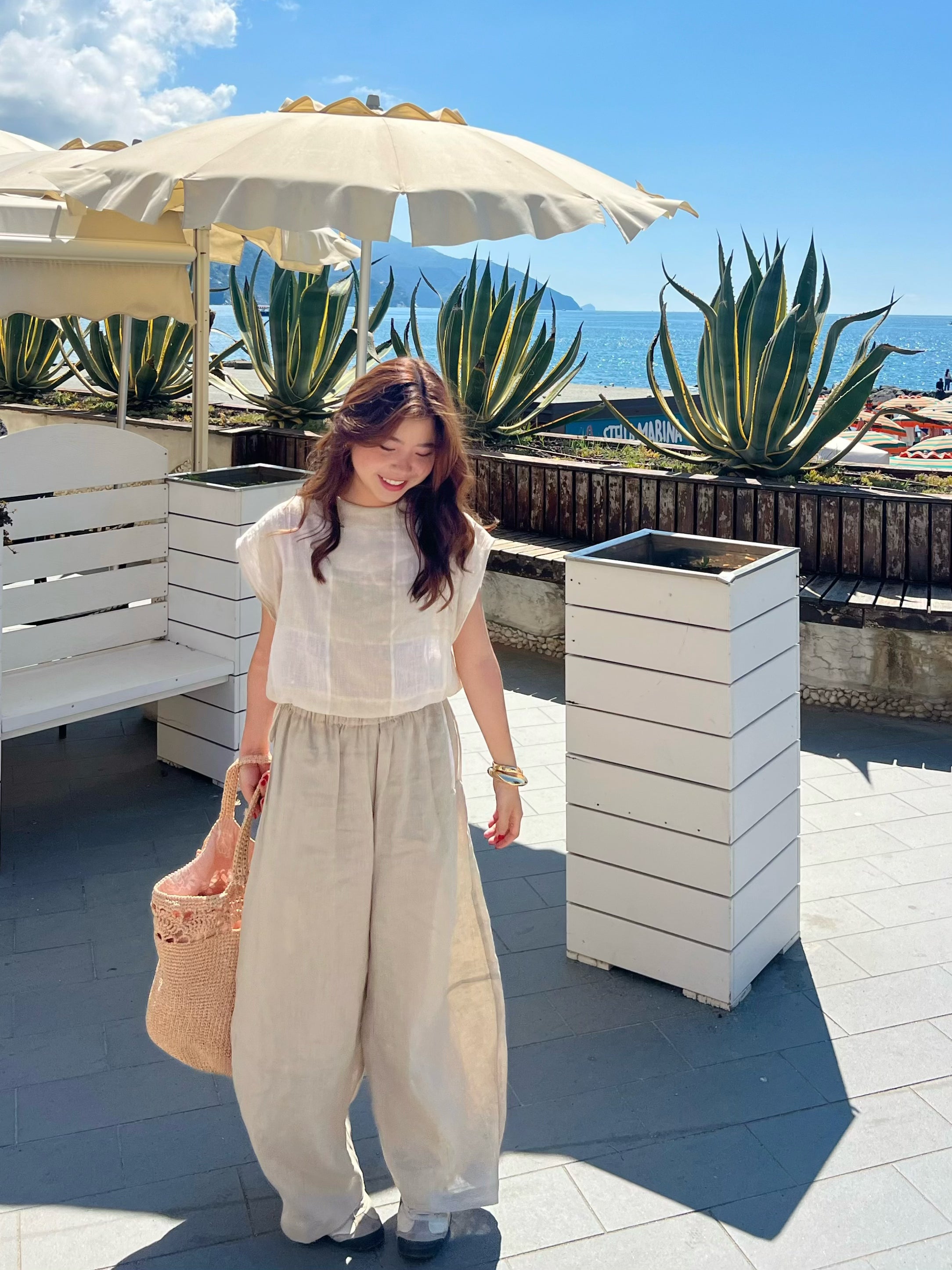 Woman wearing barrel cut linen pants on beach vacation – lightweight wide-leg trousers styled for effortless travel and summer comfort