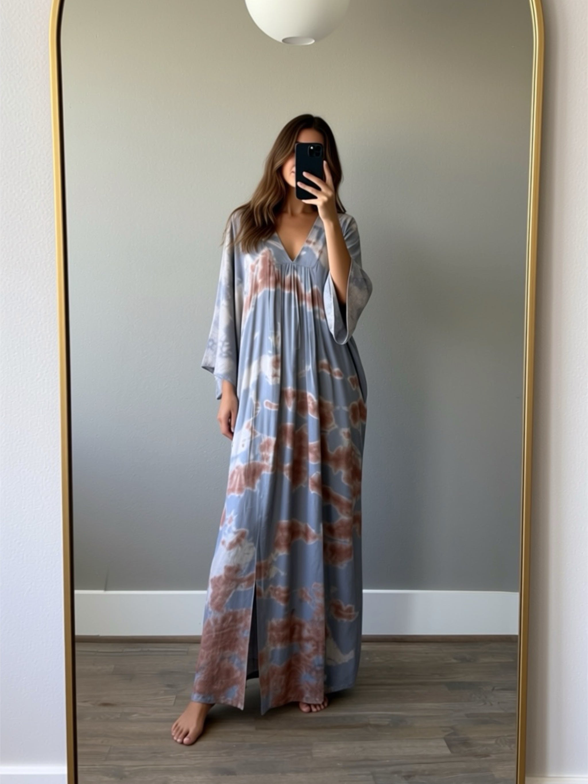 Woman wearing a tie-dye kaftan dress in front of a full-length mirror.