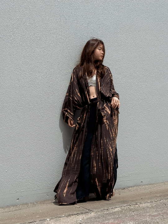 Woman wearing a handmade brown tie-dye kimono robe with long sleeves and adjustable waist tie, styled as a boho duster and lightweight beach cover-up by Coco de Chom.