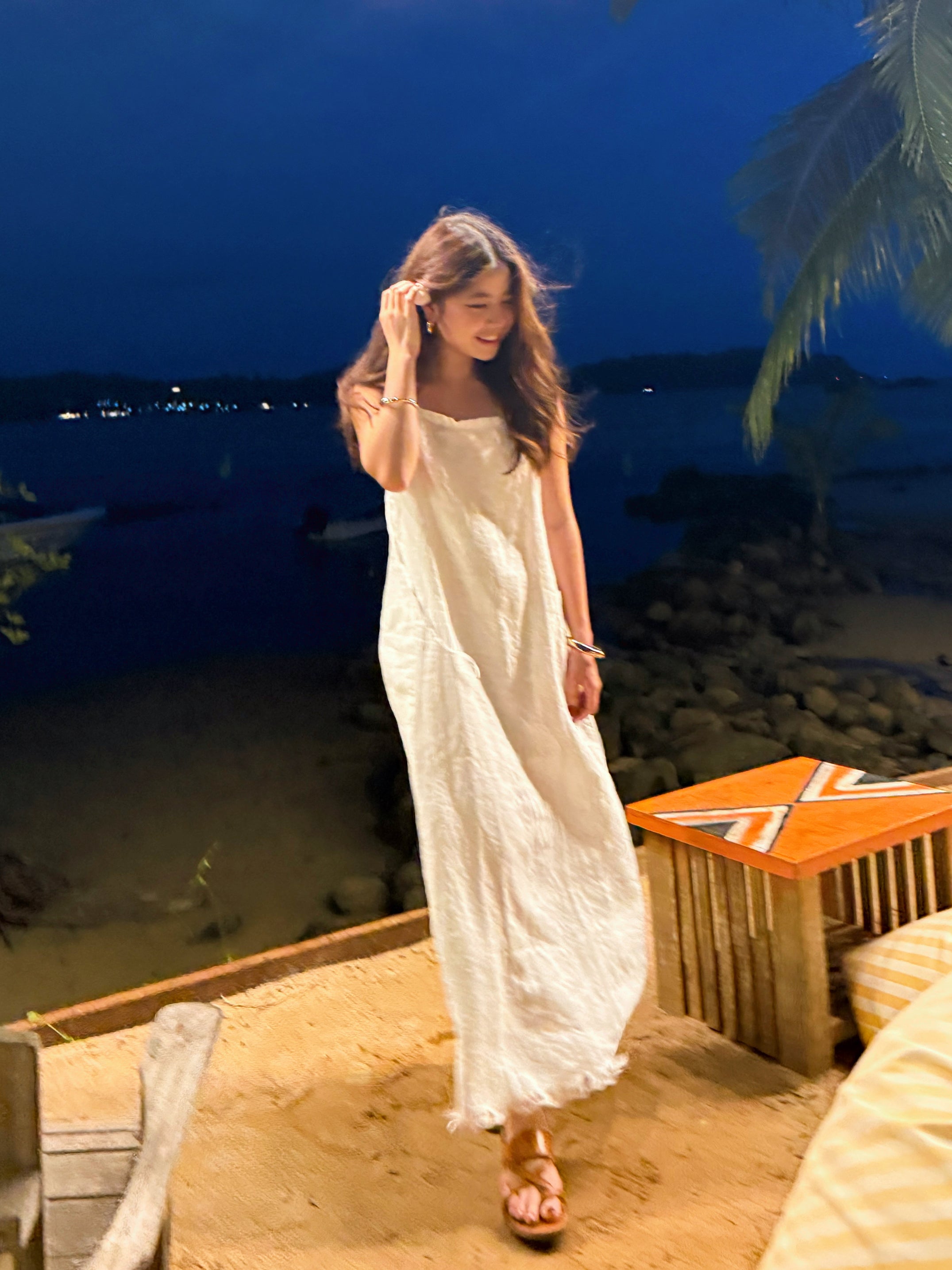 Model dancing in white linen slip dress on the beach – minimalist summer look with natural linen fabric- perfect white dress for summer – eco-friendly summer wardrobe essential