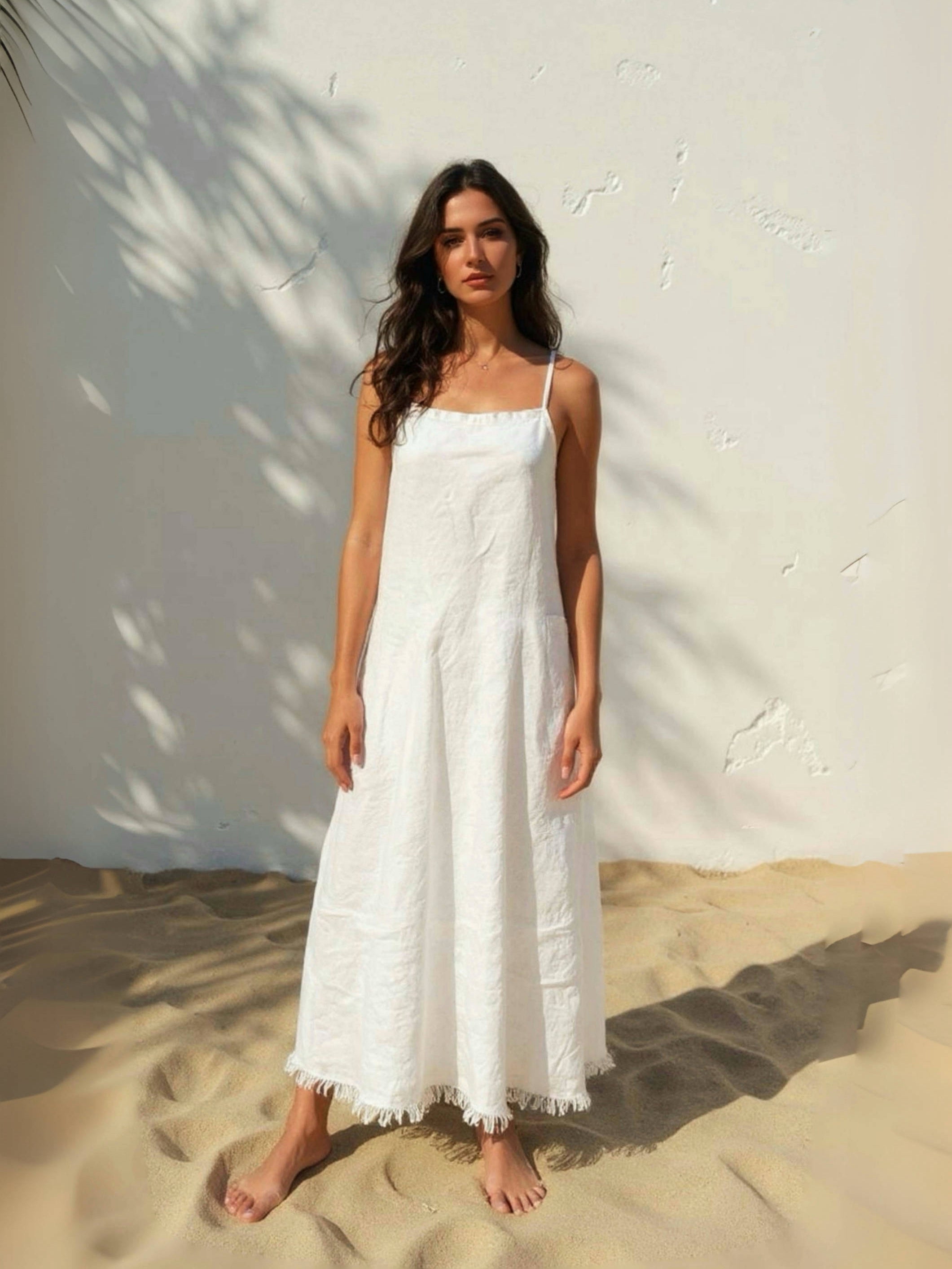 Model wearing white linen slip dress on the beach – minimalist summer look with natural linen fabric- perfect white dress for summer.