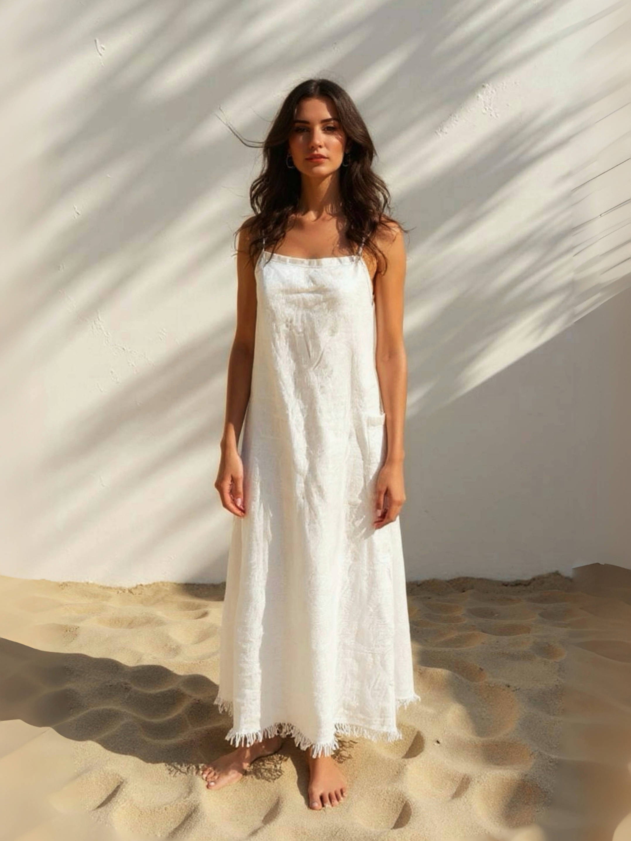 Model wearing white linen slip dress on the beach – minimalist summer look with natural linen fabric- perfect white dress for summer.