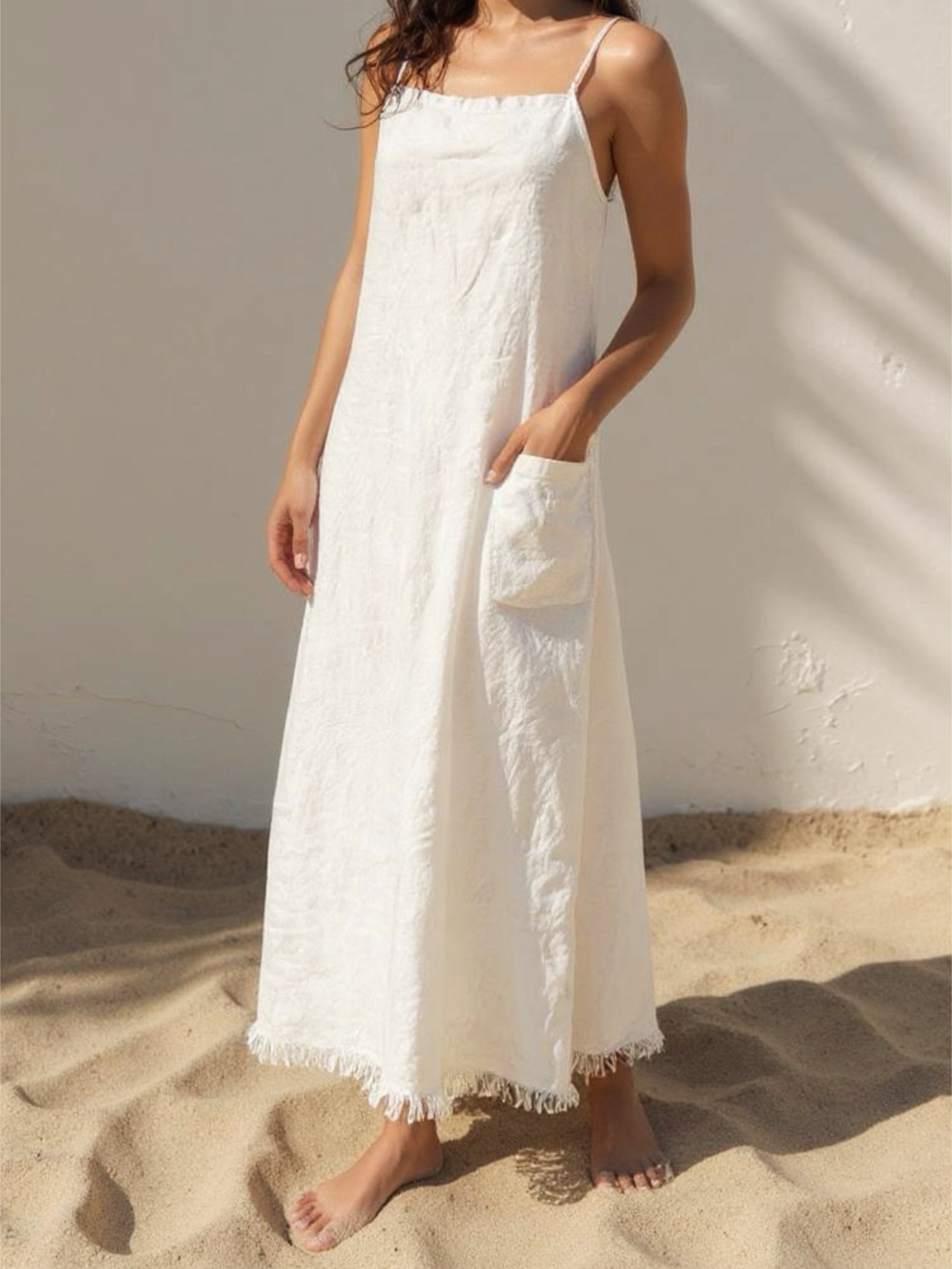 Model wearing white linen slip dress on the beach – minimalist summer look with natural linen fabric- perfect white dress for summer.