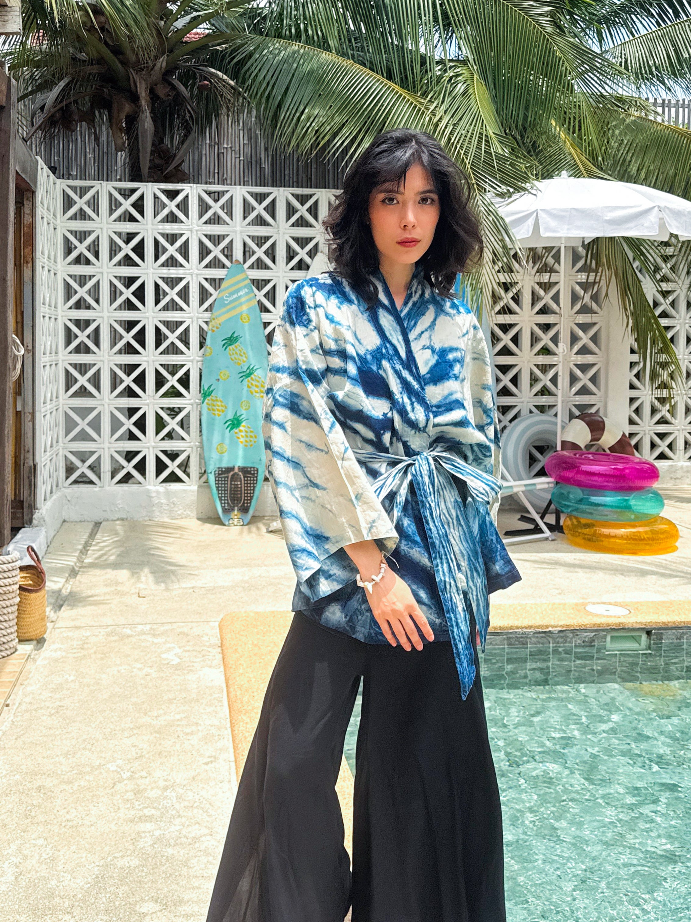 Model wearing the Limited Edition Kira Indigo Linen Kimono, artisan handmade with natural indigo Shibori tie dye. Features wide sleeves, a linen belt, and a relaxed Japanese kimono wrap silhouette. Perfect for sustainable fashion lovers seeking a boho kimono jacket or limited edition slow fashion robe from COCO DE CHOM.
