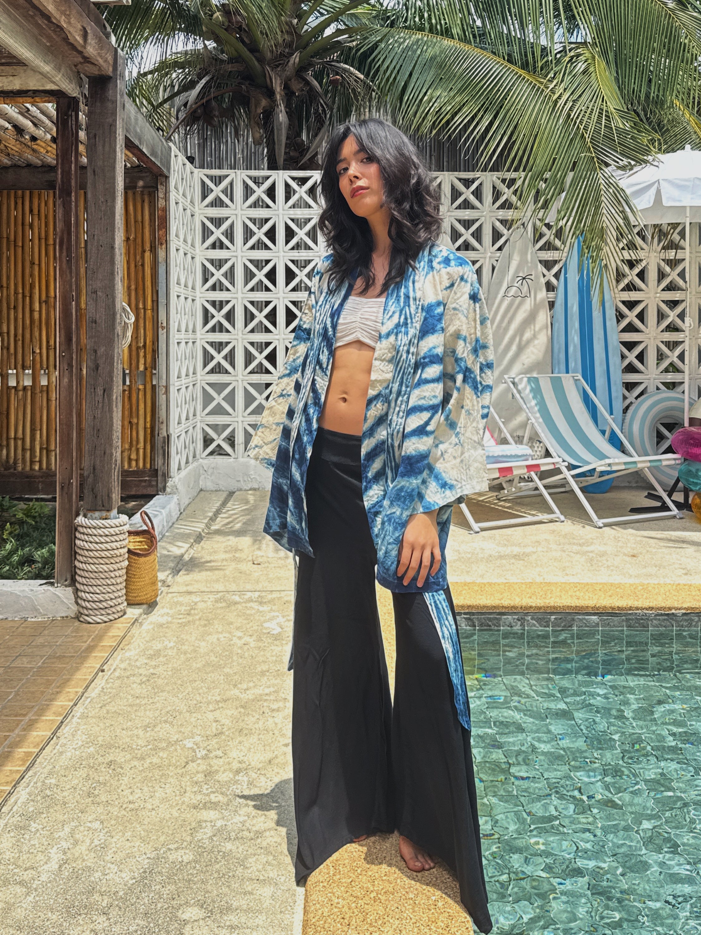 Model wearing the Limited Edition Kira Indigo Linen Kimono, artisan handmade with natural indigo Shibori tie dye. Features wide sleeves, a linen belt, and a relaxed Japanese kimono wrap silhouette. Perfect for sustainable fashion lovers seeking a boho kimono jacket or limited edition slow fashion robe from COCO DE CHOM.