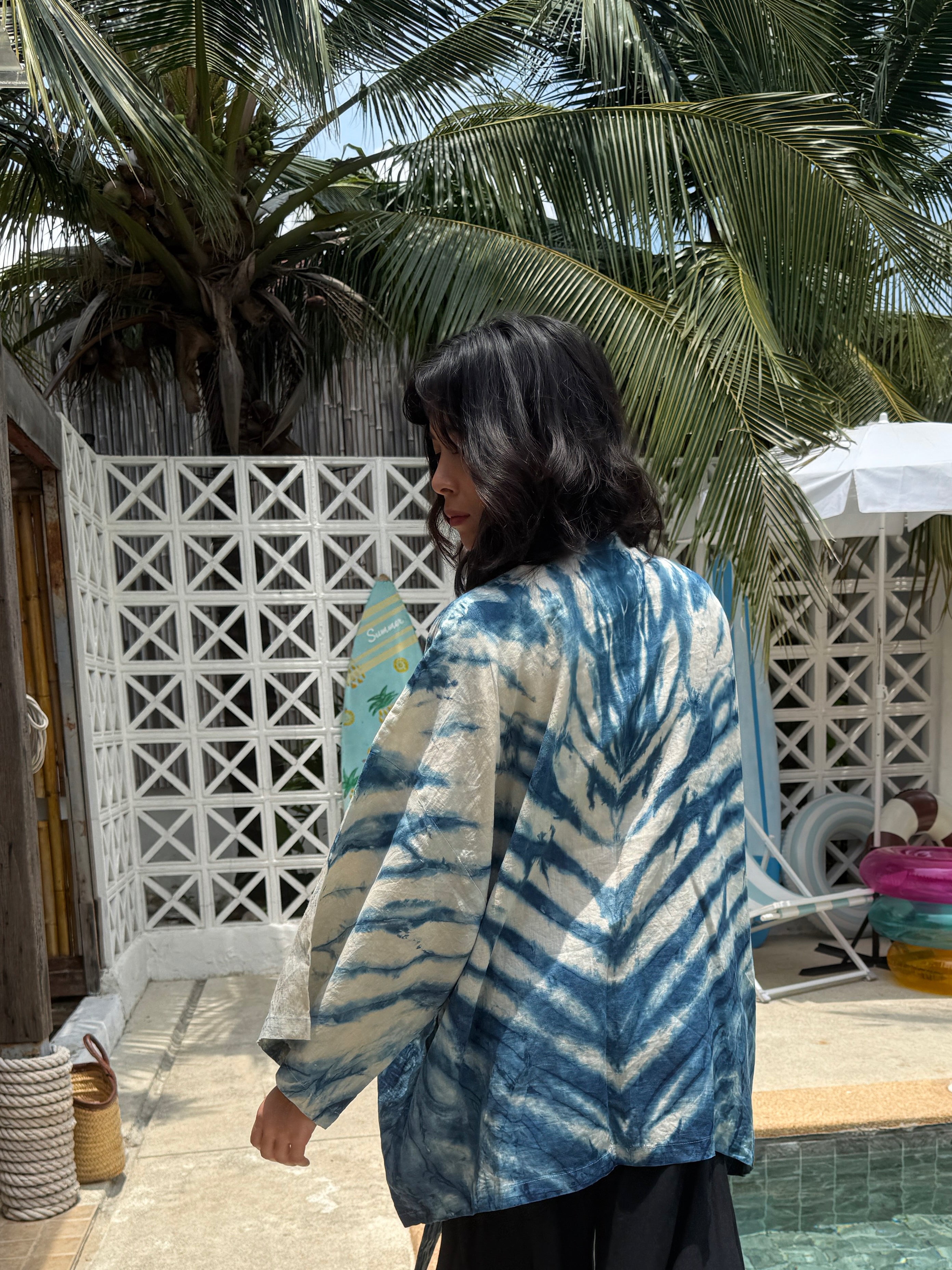 Model wearing the Limited Edition Kira Indigo Linen Kimono, artisan handmade with natural indigo Shibori tie dye. Features wide sleeves, a linen belt, and a relaxed Japanese kimono wrap silhouette. Perfect for sustainable fashion lovers seeking a boho kimono jacket or limited edition slow fashion robe from COCO DE CHOM.