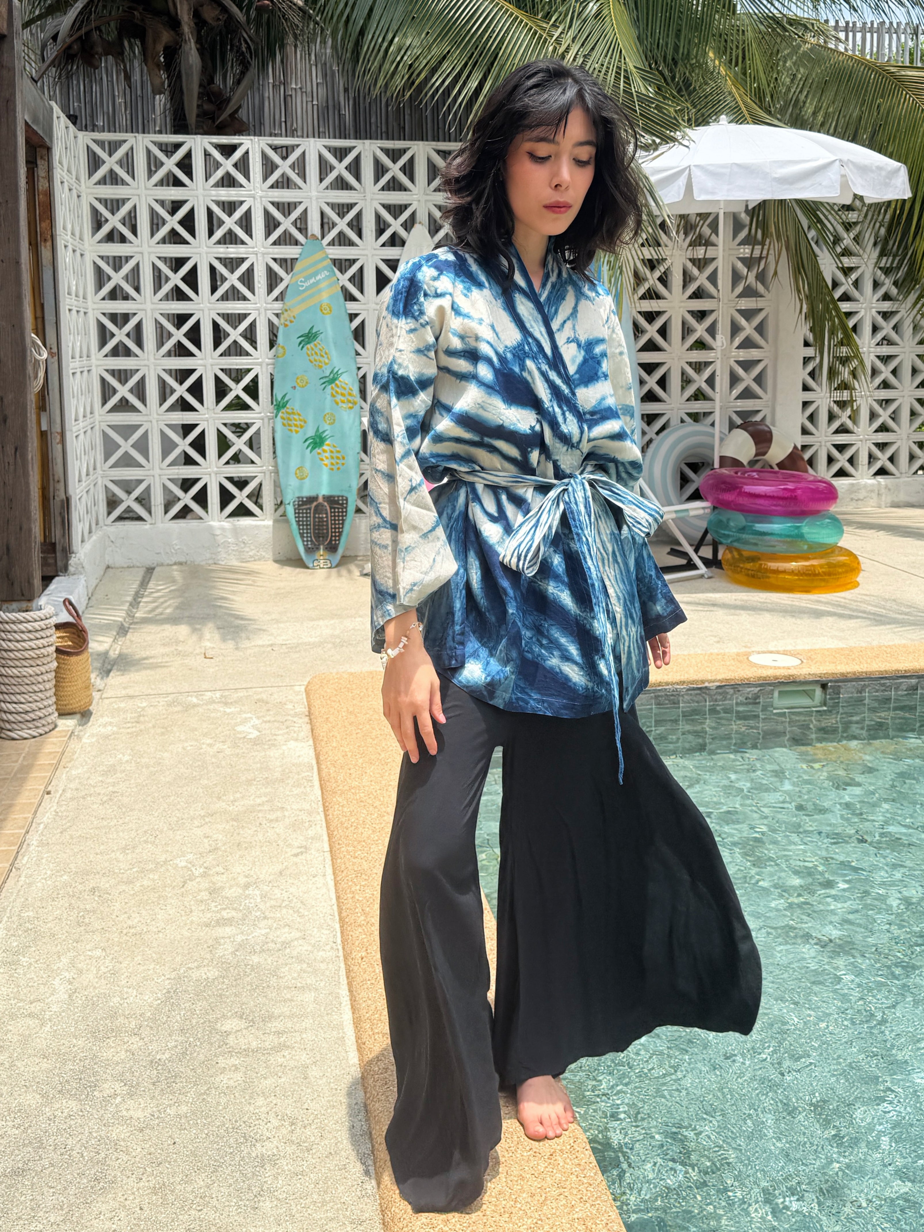 Model wearing the Limited Edition Kira Indigo Linen Kimono, artisan handmade with natural indigo Shibori tie dye. Features wide sleeves, a linen belt, and a relaxed Japanese kimono wrap silhouette. Perfect for sustainable fashion lovers seeking a boho kimono jacket or limited edition slow fashion robe from COCO DE CHOM.