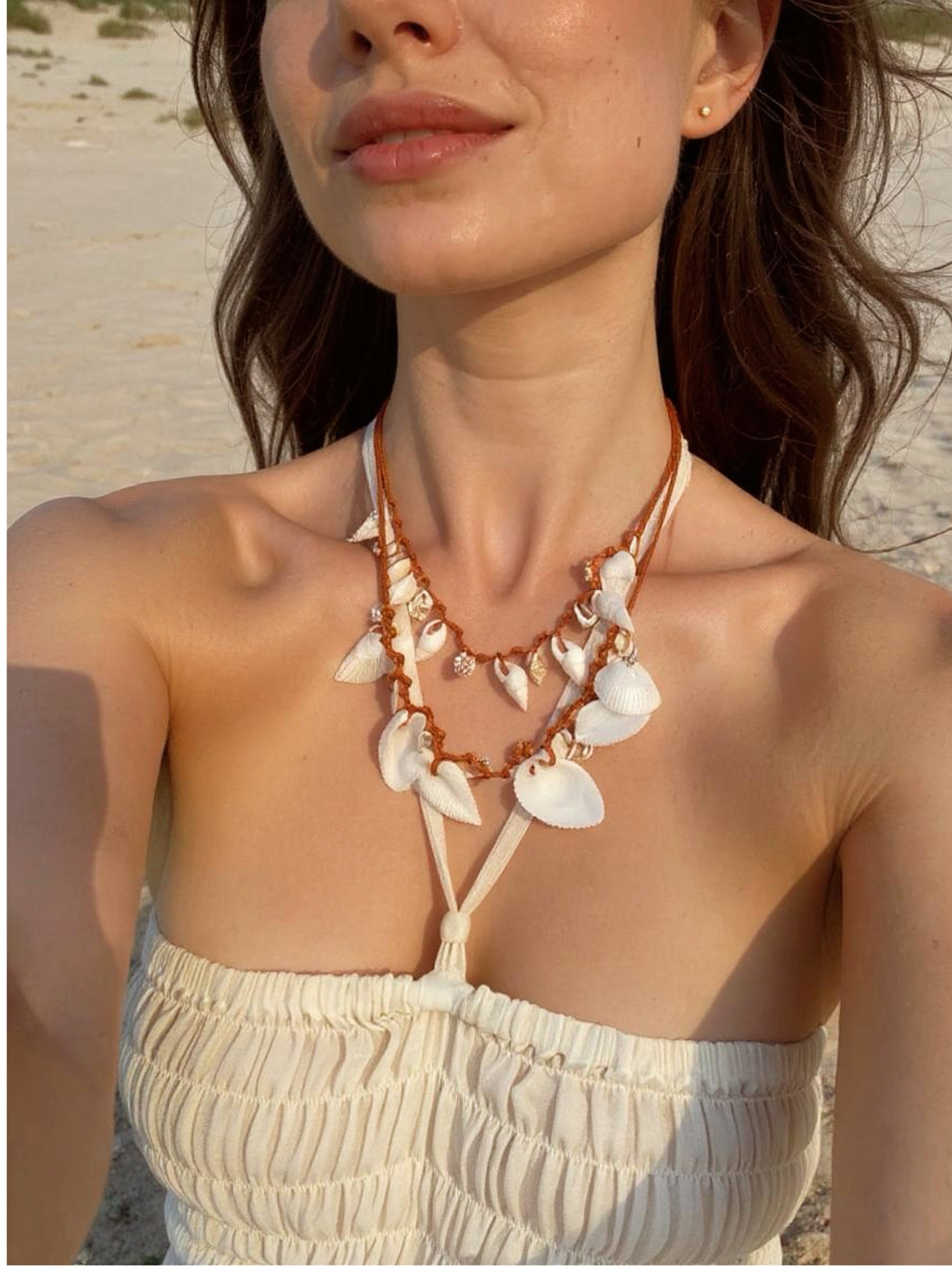Model wearing a handmade white seashell choker necklace with boho beach style, photographed outdoors in natural light, styled with relaxed resortwear.