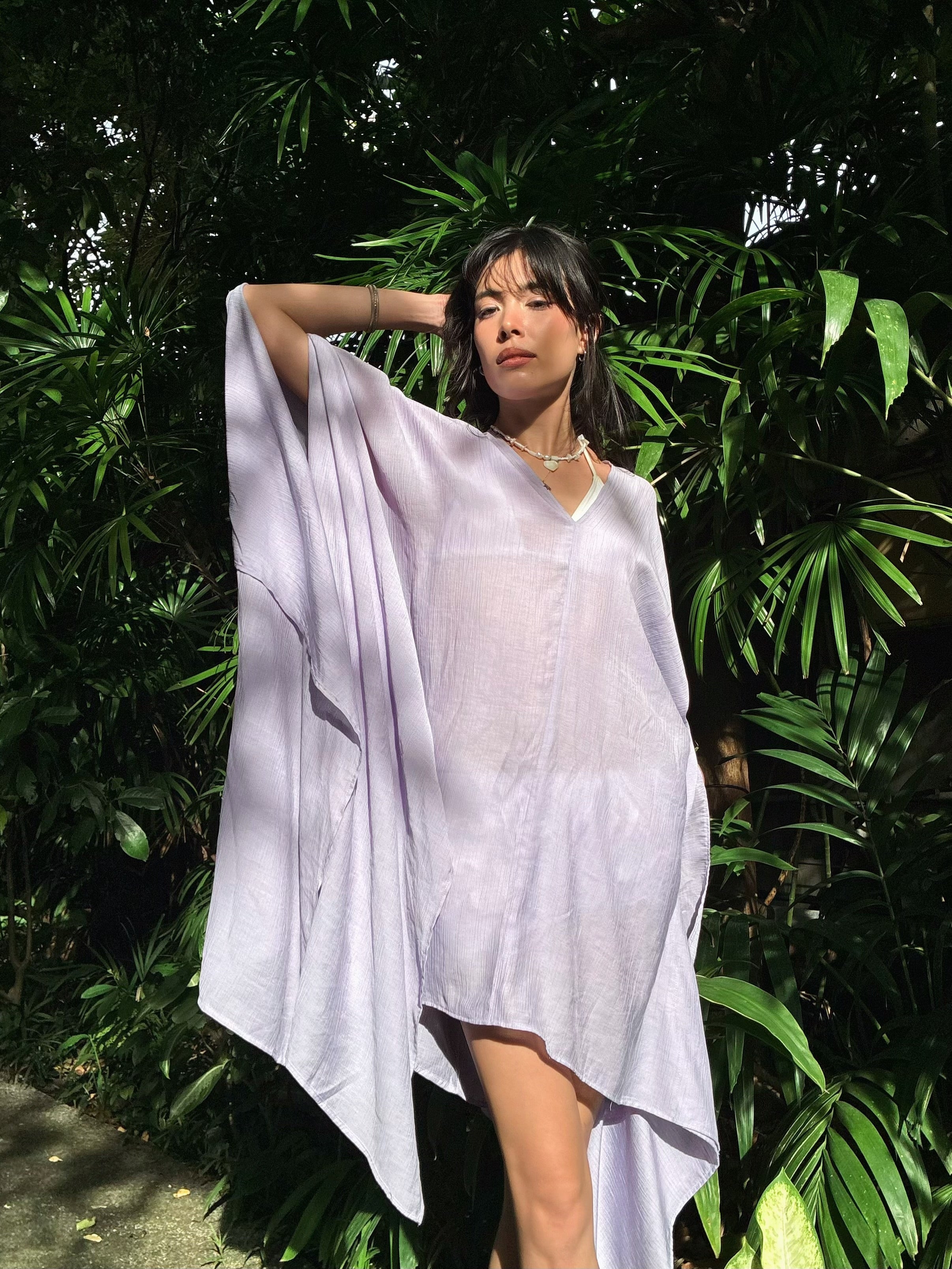 A woman wearing a lavender Mini Kaftan Cover Up, flowy oversized beach cover up and resort top with deep V neckline for poolside lounging and cruise outfits
