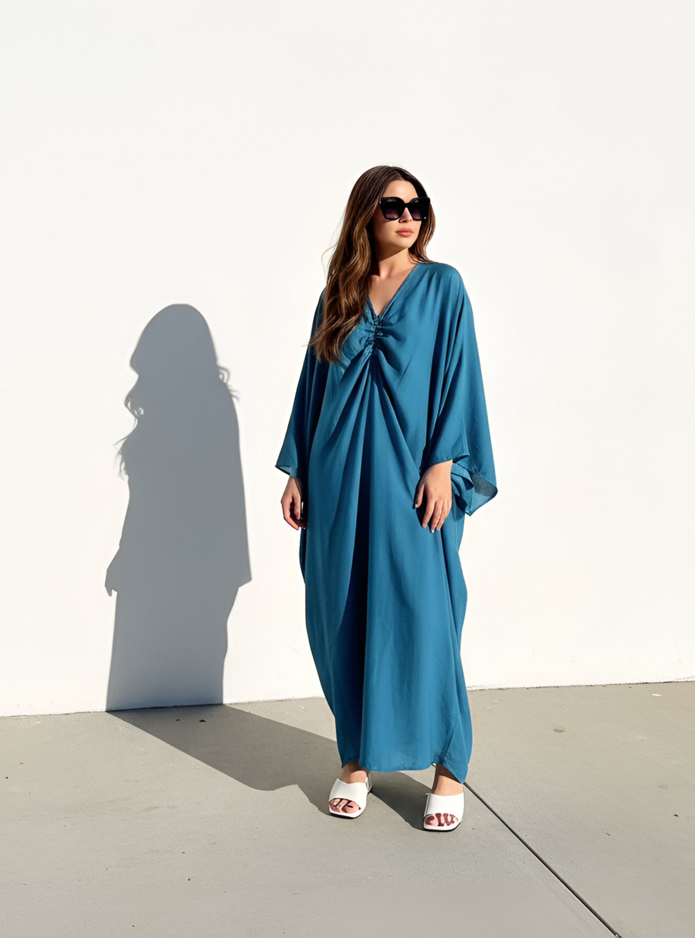 Woman wearing a teal blue resort caftan maxi dress, oversized plus size cover up with relaxed sleeves and elegant drape—perfect for pool, beach, and cruise
