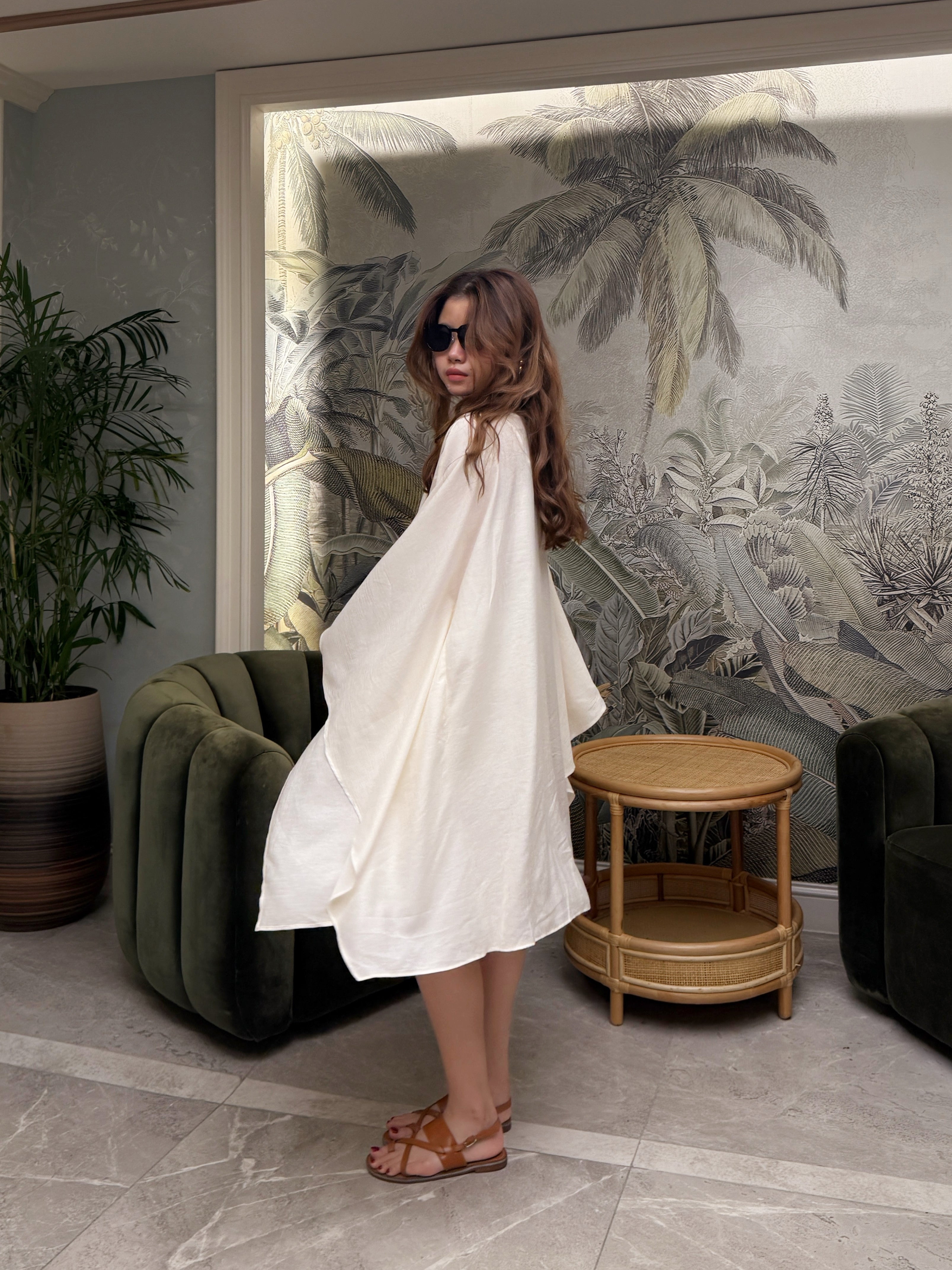 Woman wearing a white mini kaftan top beach cover up tunic, one size fits most, long sleeves with high-low hem, lightweight resort vacation wear, standing in a resort vibe.