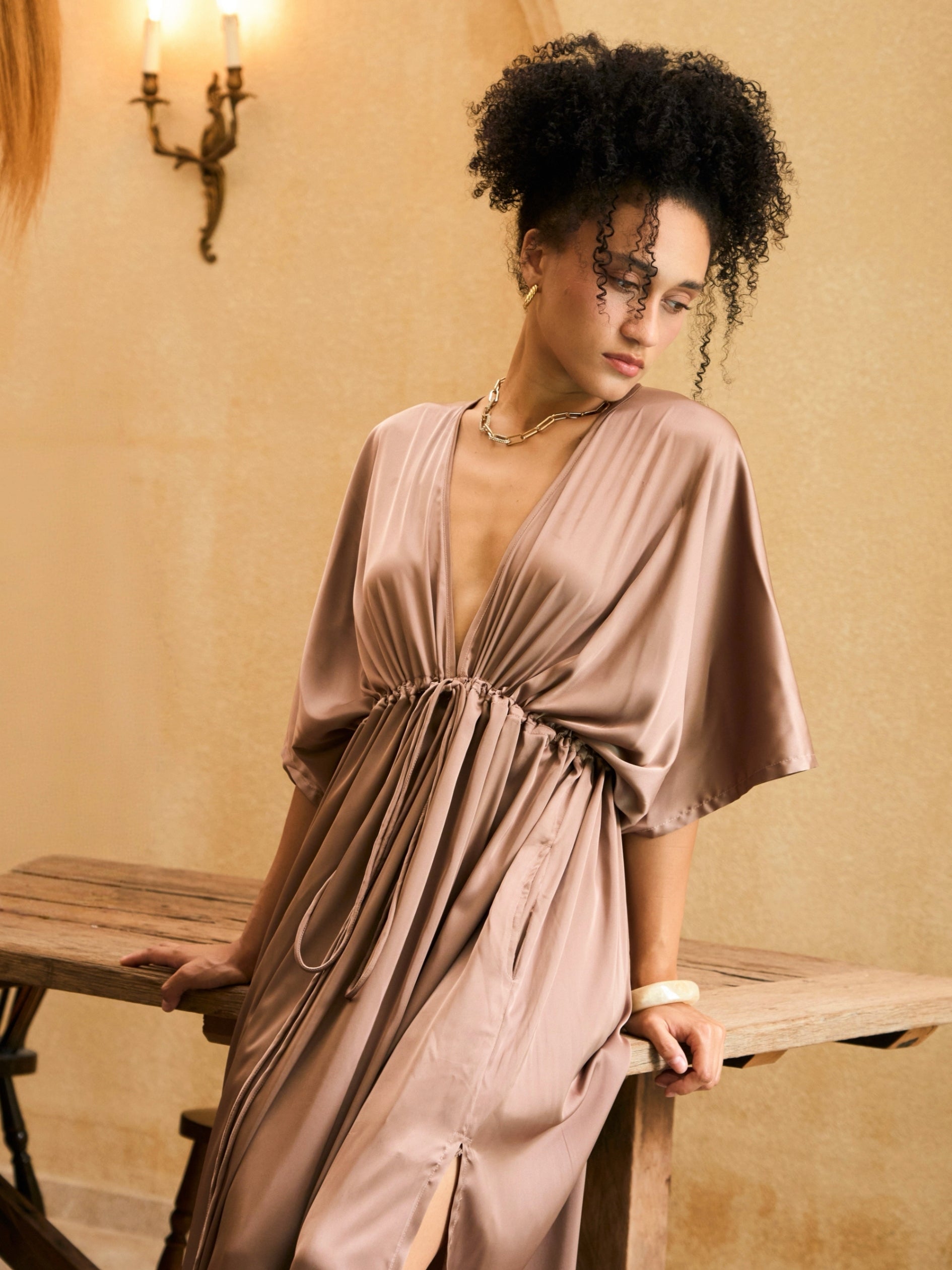 Woman wearing a mocha rose kaftan maxi dress with deep V-neck and self-tie waist, styled as resort wear and a beach wedding guest dress