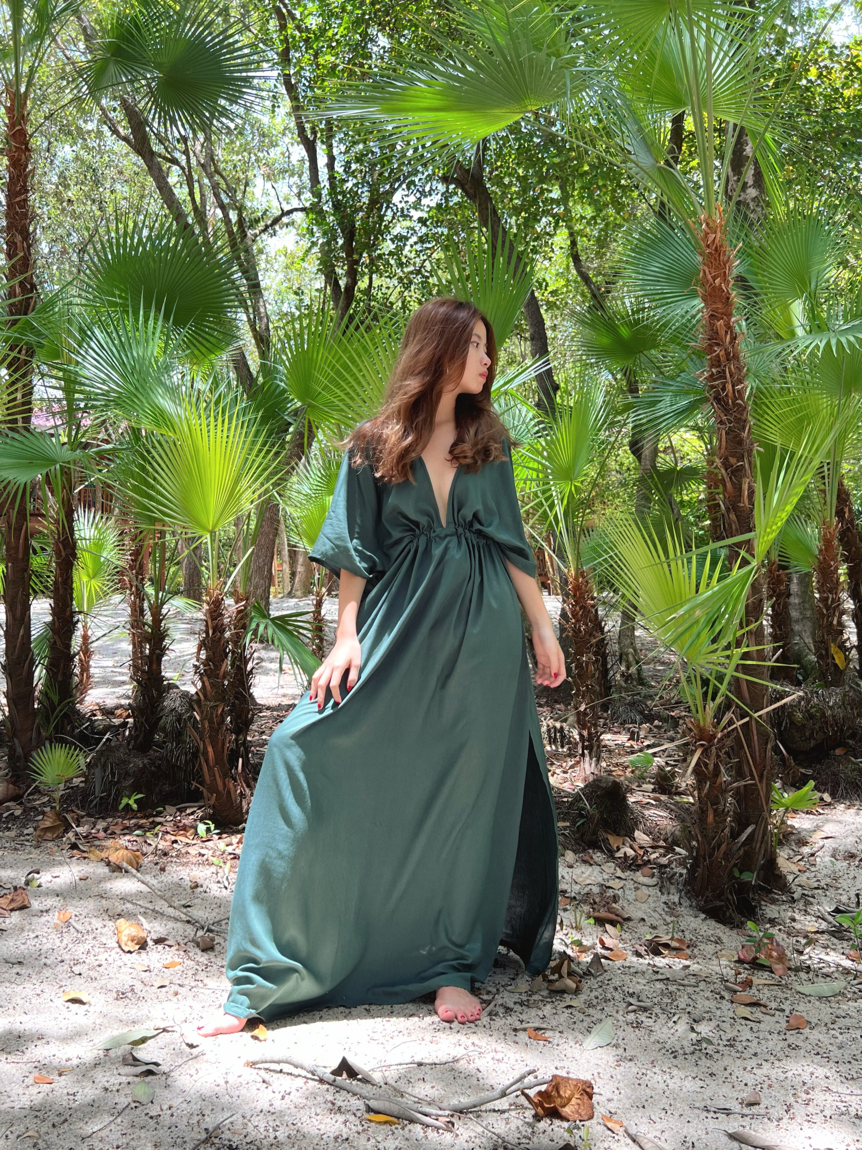Woman wearing a flowy tie-dye kaftan maxi dress on the beach, featuring a deep V-neck, side slit, and cinched waist—handmade resortwear by Coco de Chom