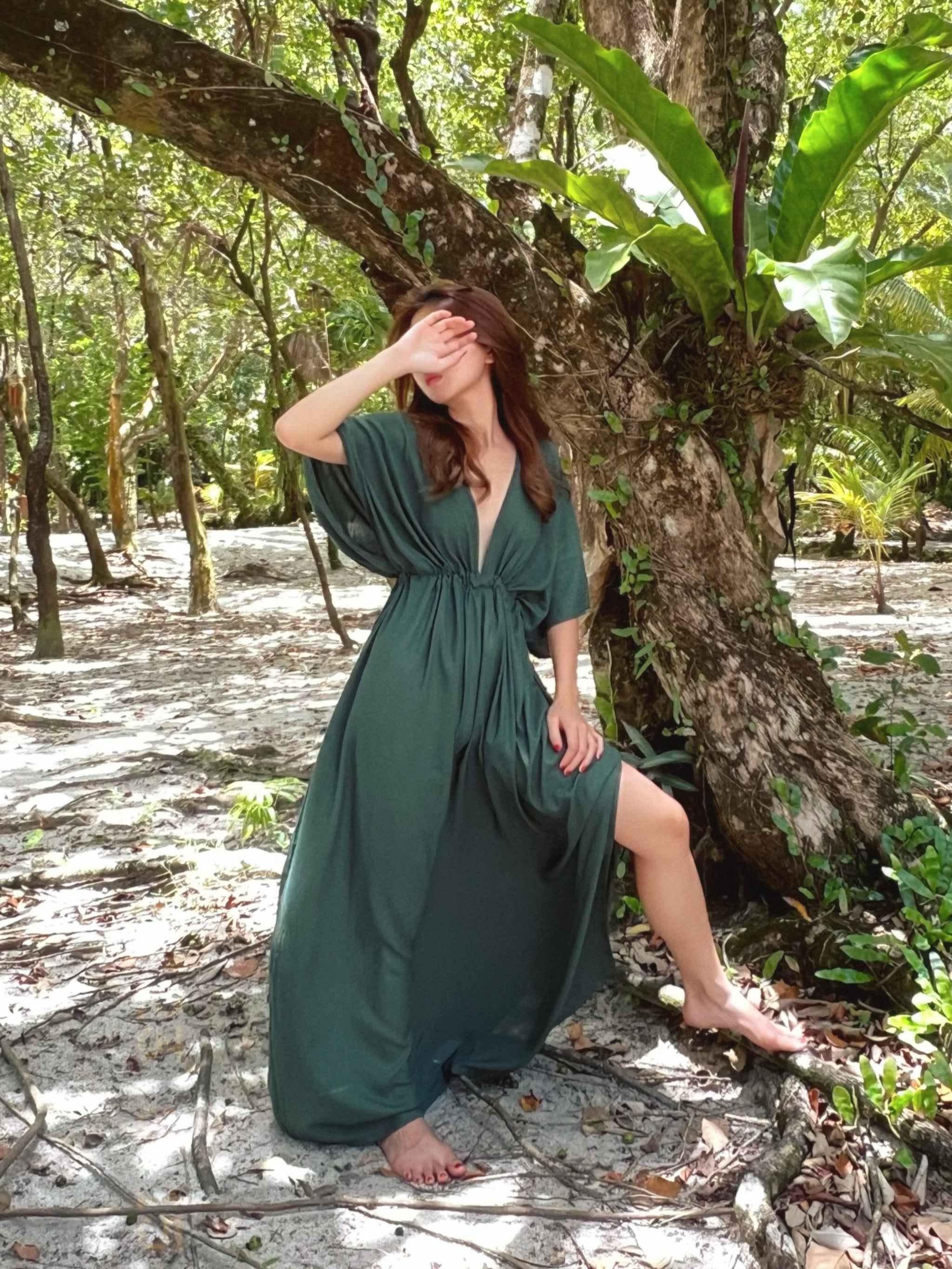 Woman wearing a flowy tie-dye kaftan maxi dress on the beach, featuring a deep V-neck, side slit, and cinched waist—handmade resortwear by Coco de Chom