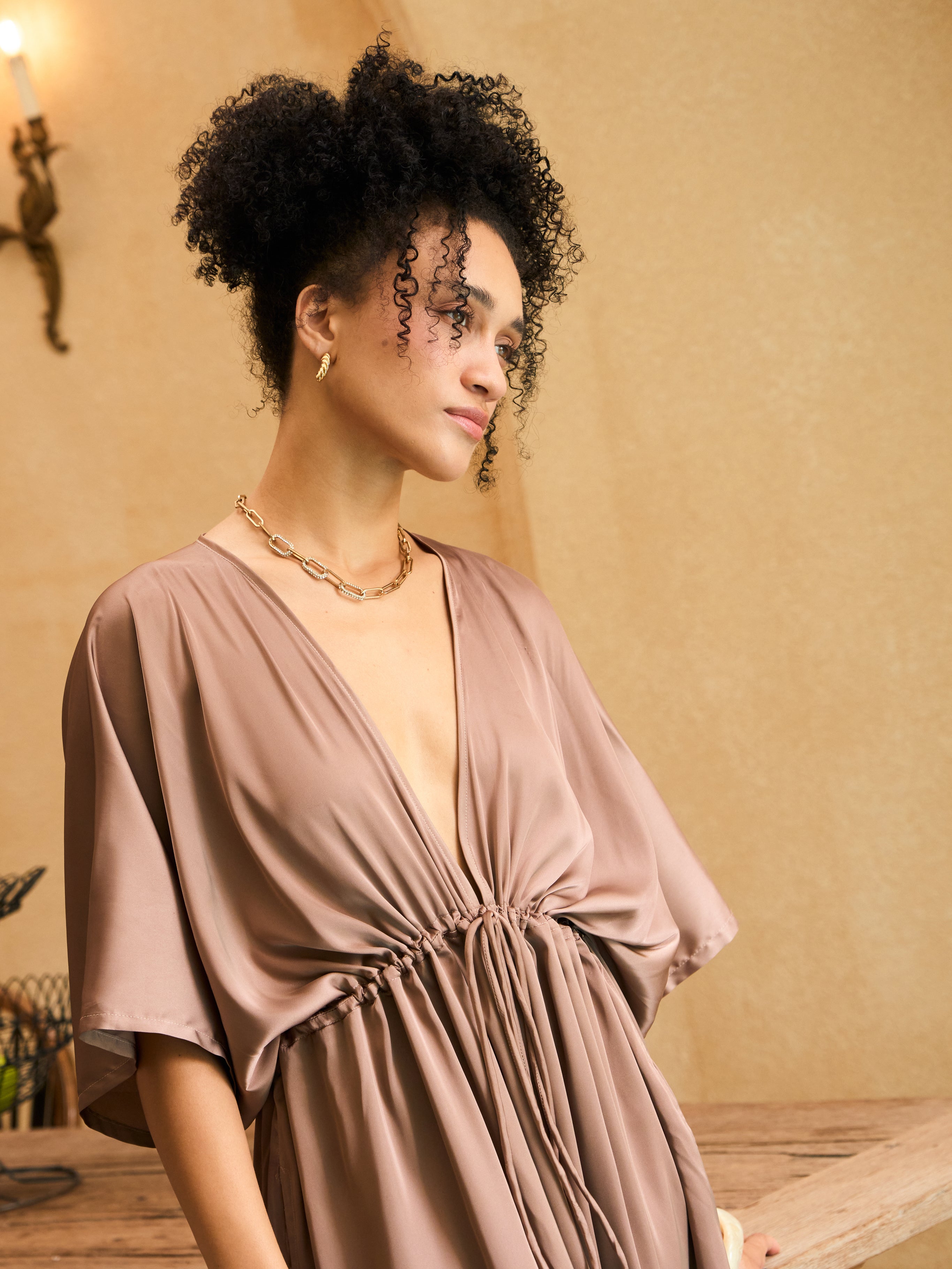 Woman wearing a mocha rose kaftan maxi dress with deep V-neck and self-tie waist, styled as resort wear and a beach wedding guest dress