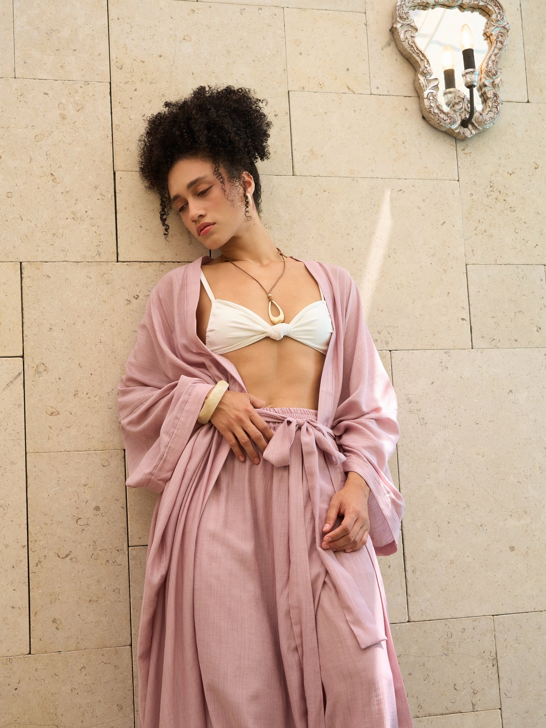 Woman wearing oversized mauve blush kimono kaftan as lightweight resort cover up, styled for beach and vacation wear by COCO DE CHOM