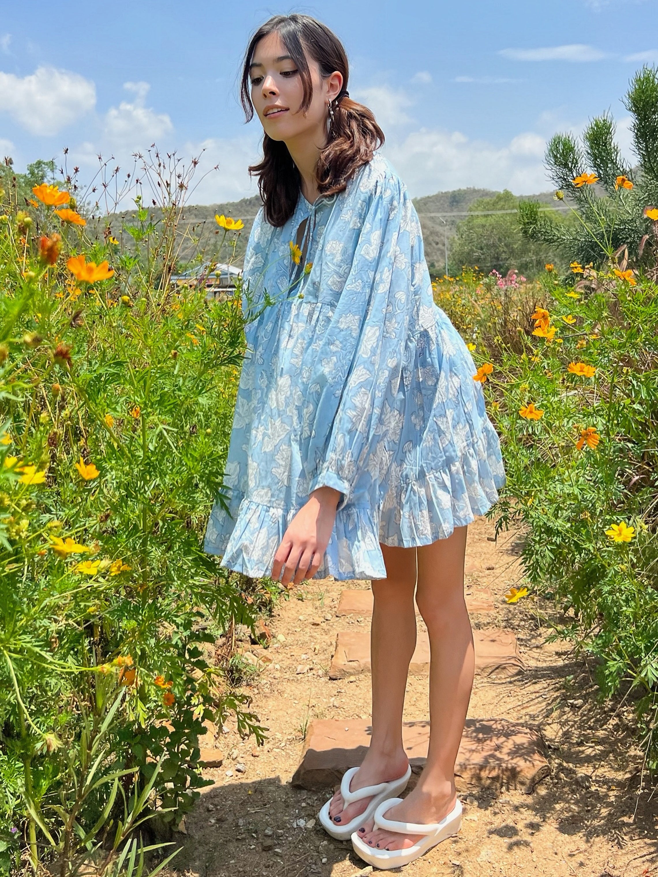 Shop Coco de Chom Lola Bohemian Mini Dress in Beautiful Blue Sky - A Truly Unique Limited Edition Piece. Handcrafted with Wooden Blocks on Fine Cotton Voile, Showcasing a Dreamy Block Printed Pattern Inspired by Bougainvillea Flowers and Vacations. Ideal for Beach Days, Vacations, and Boho Enthusiasts.