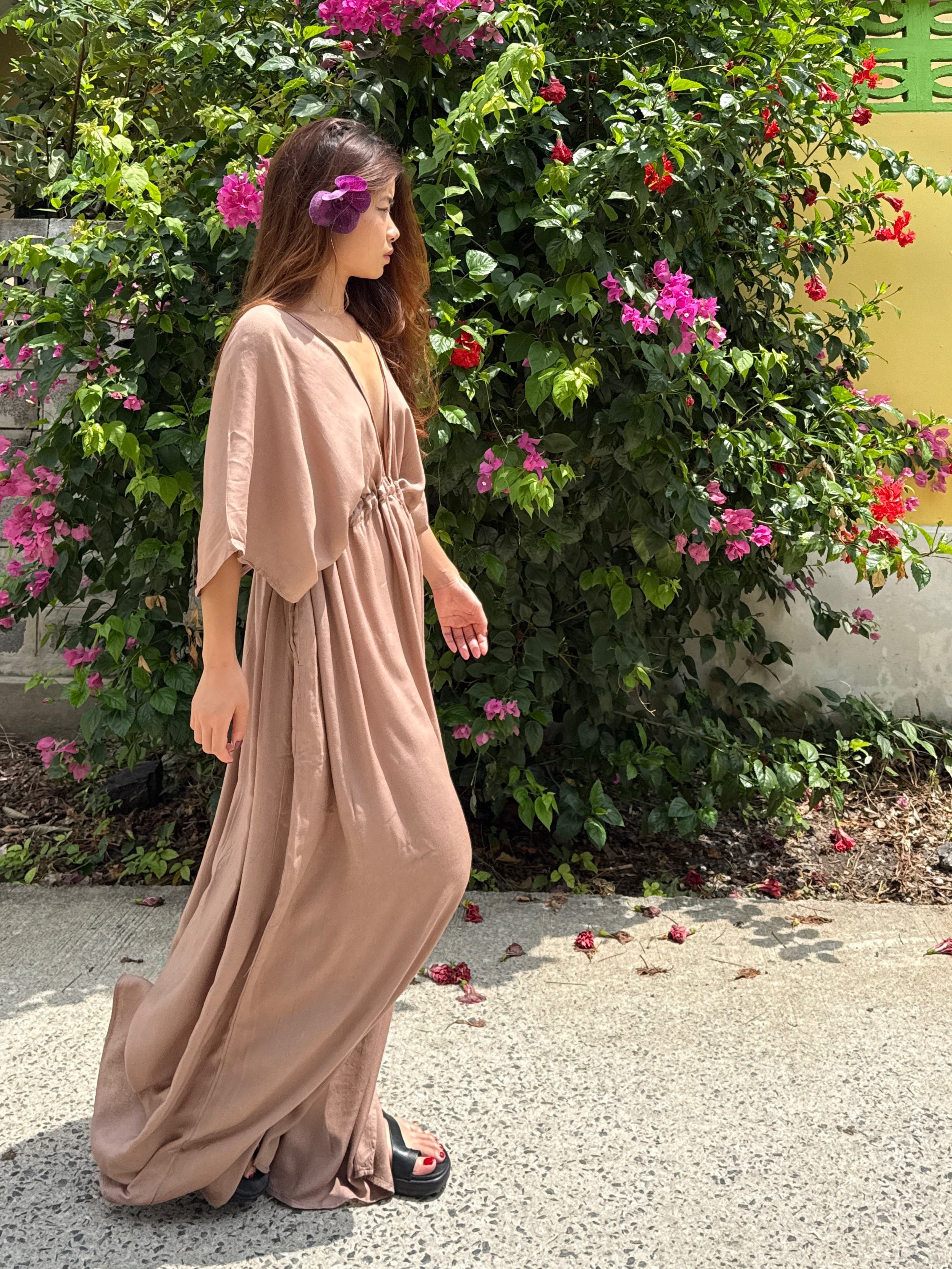 long kaftan dress in nude worn by the resort style, oversized beach cover up and plus size friendly resort maxi dress with deep V neckline, side slit, and flowy silhouette