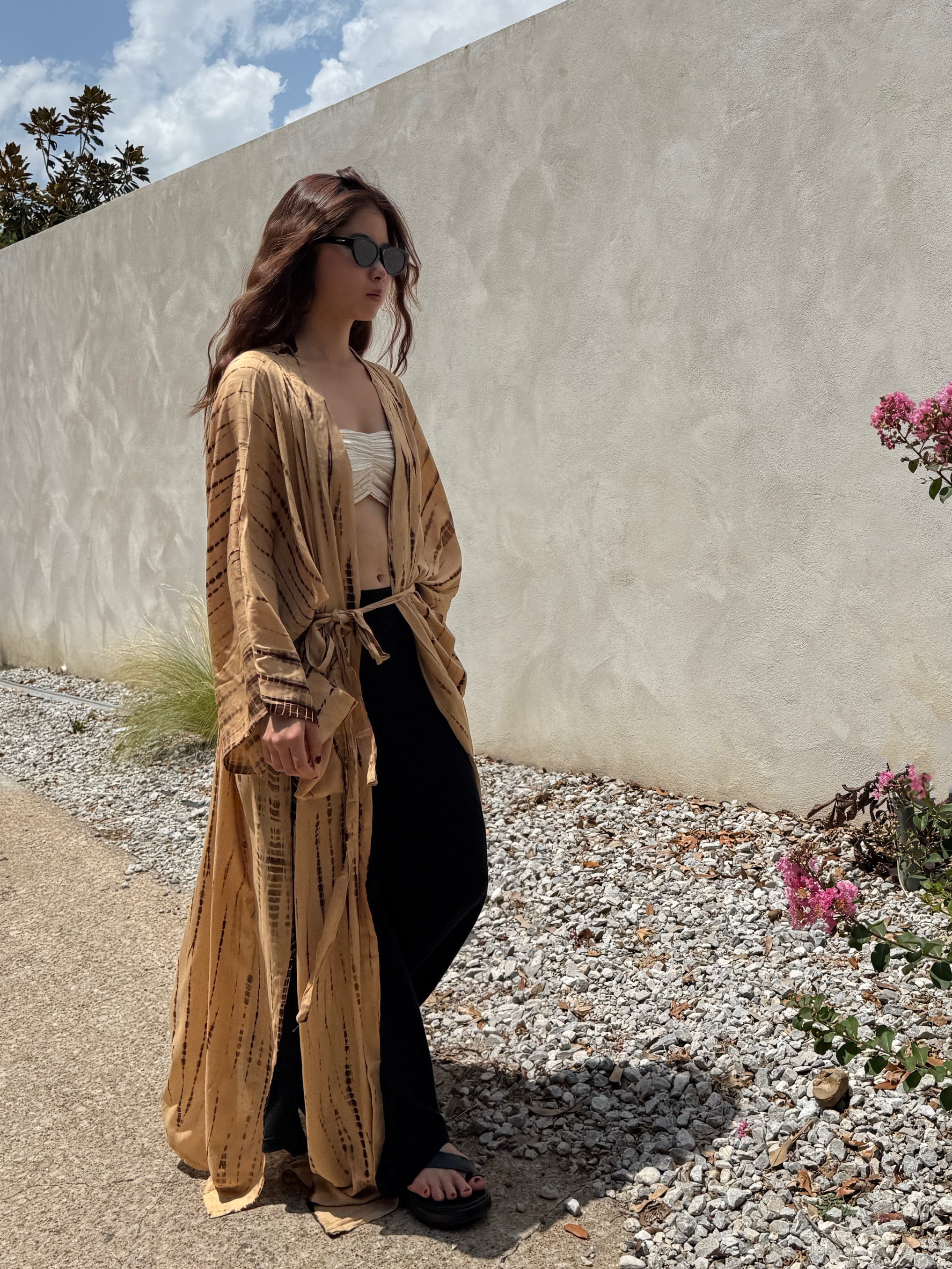Woman wearing a tan tie-dye long kimono robe from Coco de Chom. The oversized robe features long sleeves, a waist tie, and a relaxed, boho-style fit.