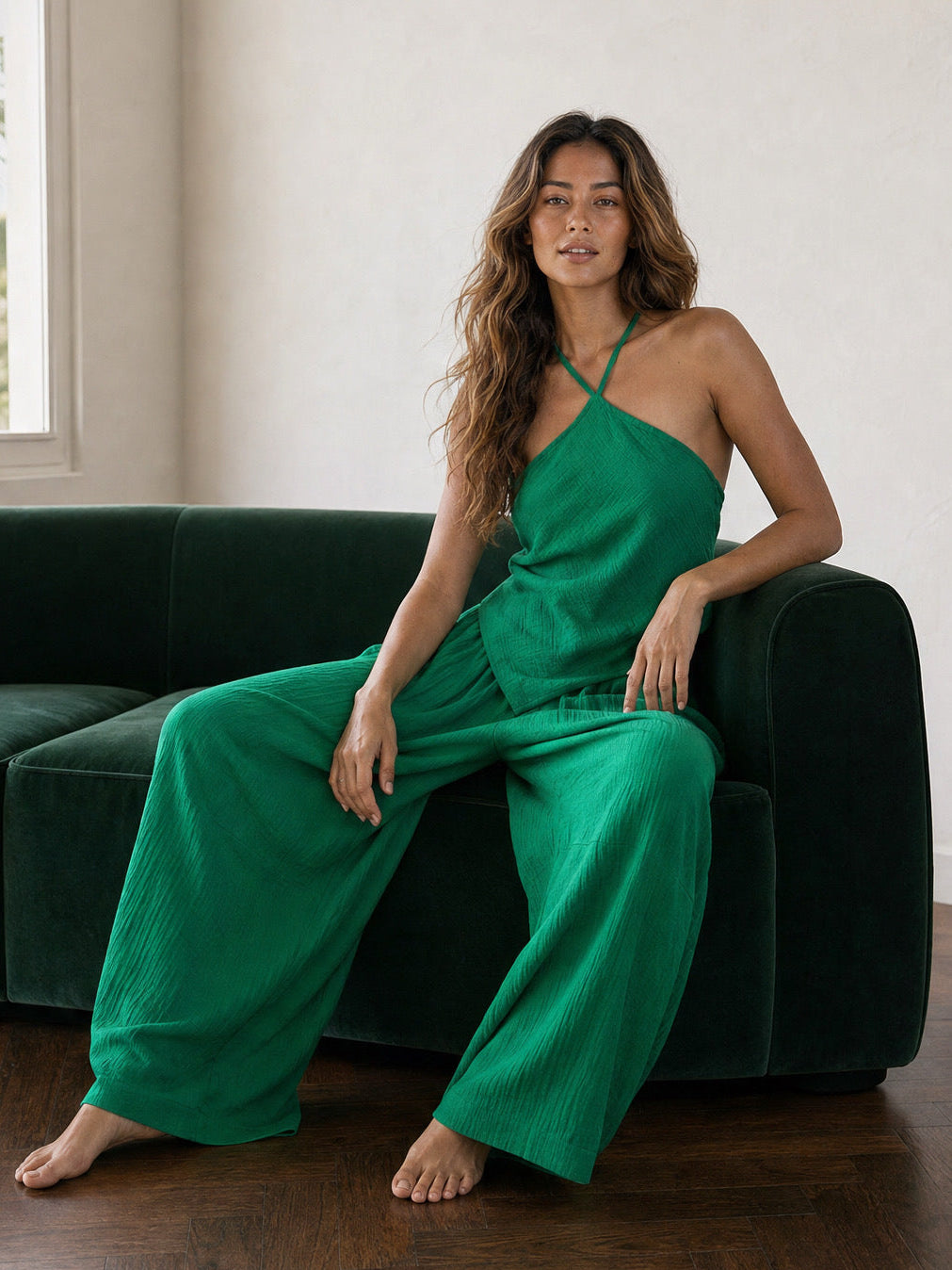 Woman wearing an emerald green handkerchief halter top and matching wide leg pants, boho vacation outfit and resort wear set for beach travel