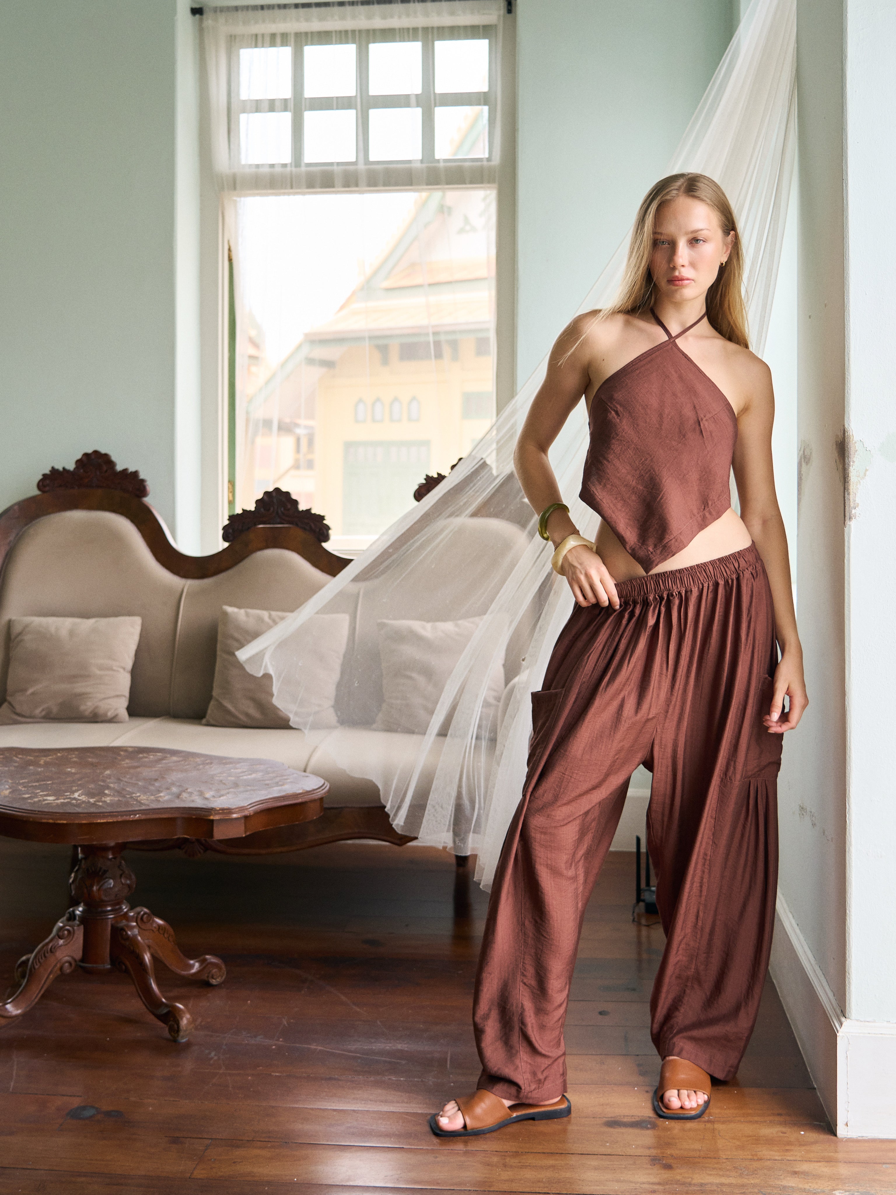 Model wearing cocoa brown wide-leg pants with a matching halter top, a chic vacation outfit perfect for festival style, beach days, and resort wear.