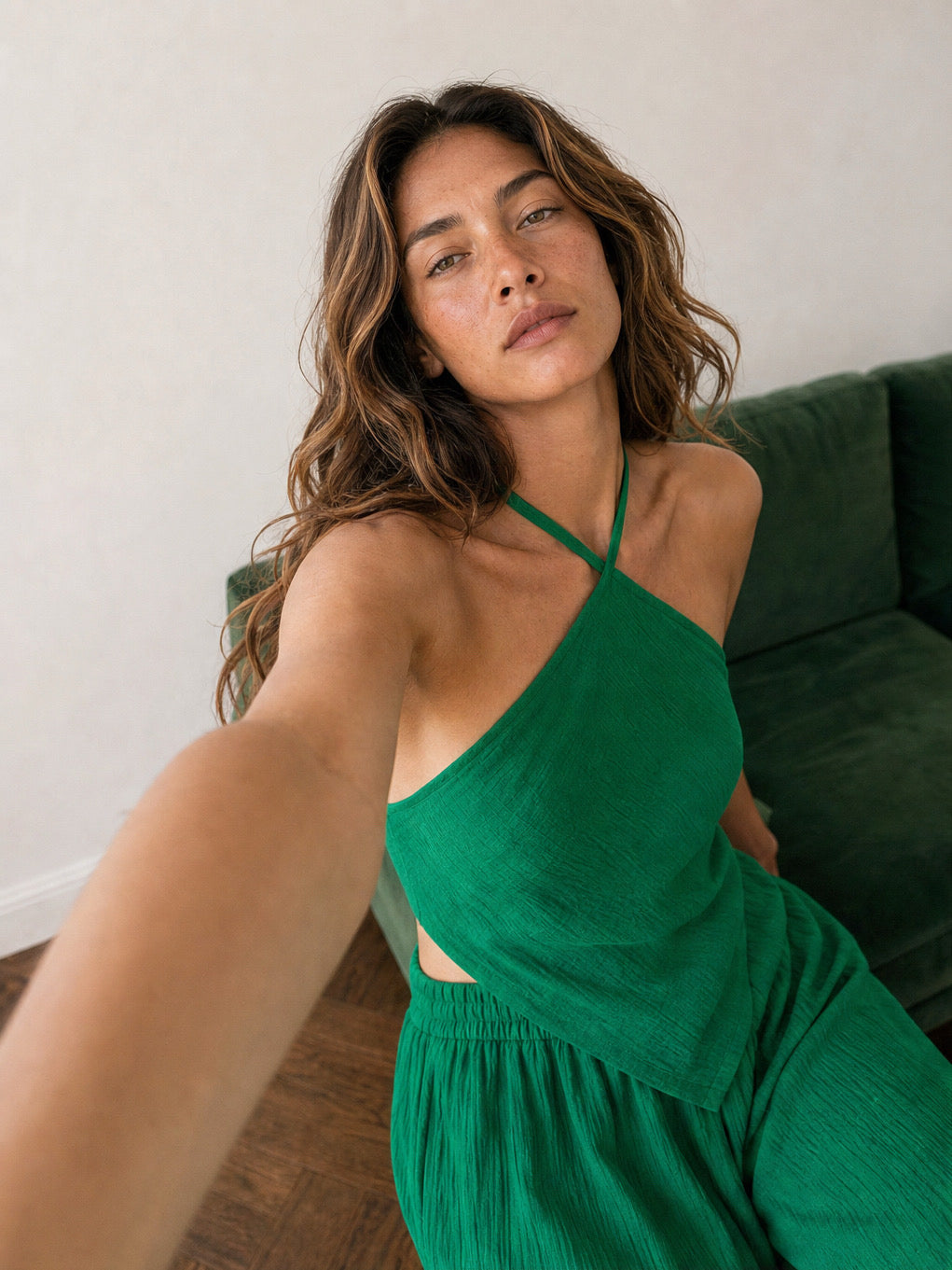 Woman wearing an emerald green handkerchief halter top and matching wide leg pants, boho vacation outfit and resort wear set for beach travel