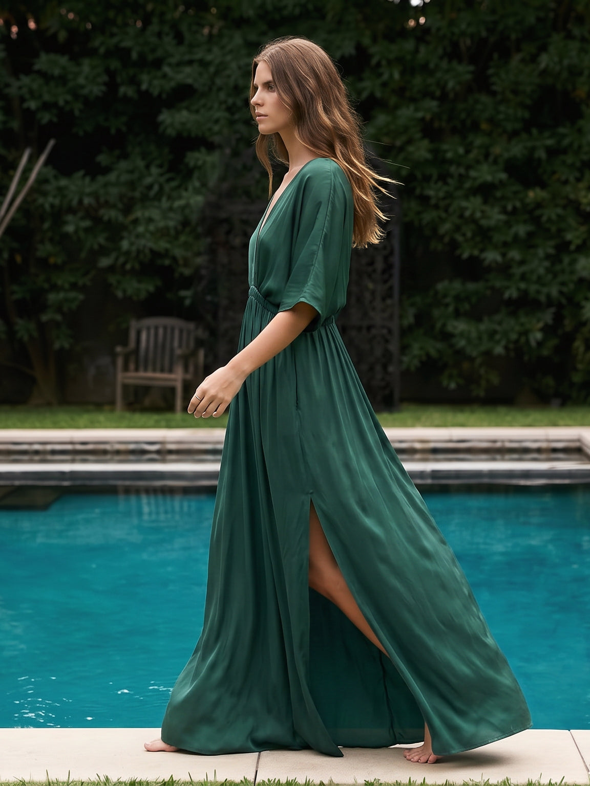 Woman wearing a handmade green kaftan maxi dress on the beach, featuring a deep V-neck, side slit, and cinched waist—handmade resortwear by Coco de Chom