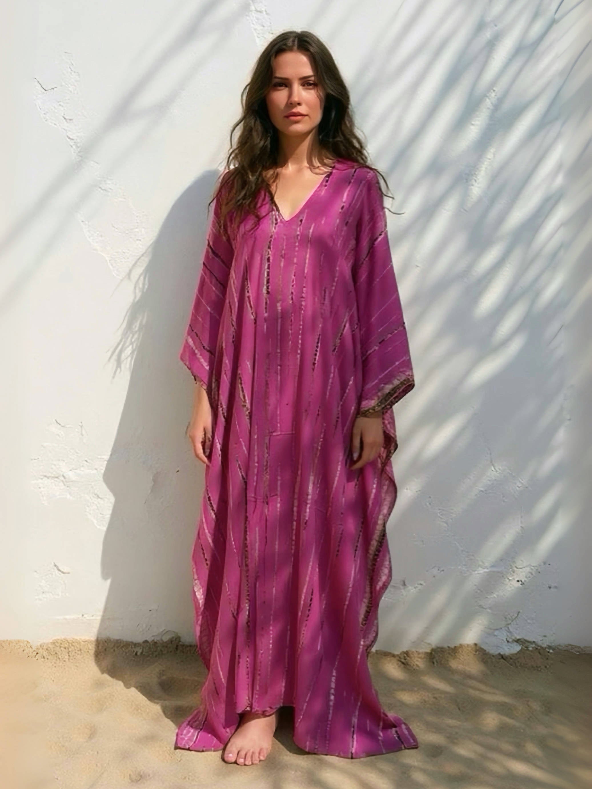Woman wearing a handmade tie dye pink dress standing against a white wall with shadows, boho look