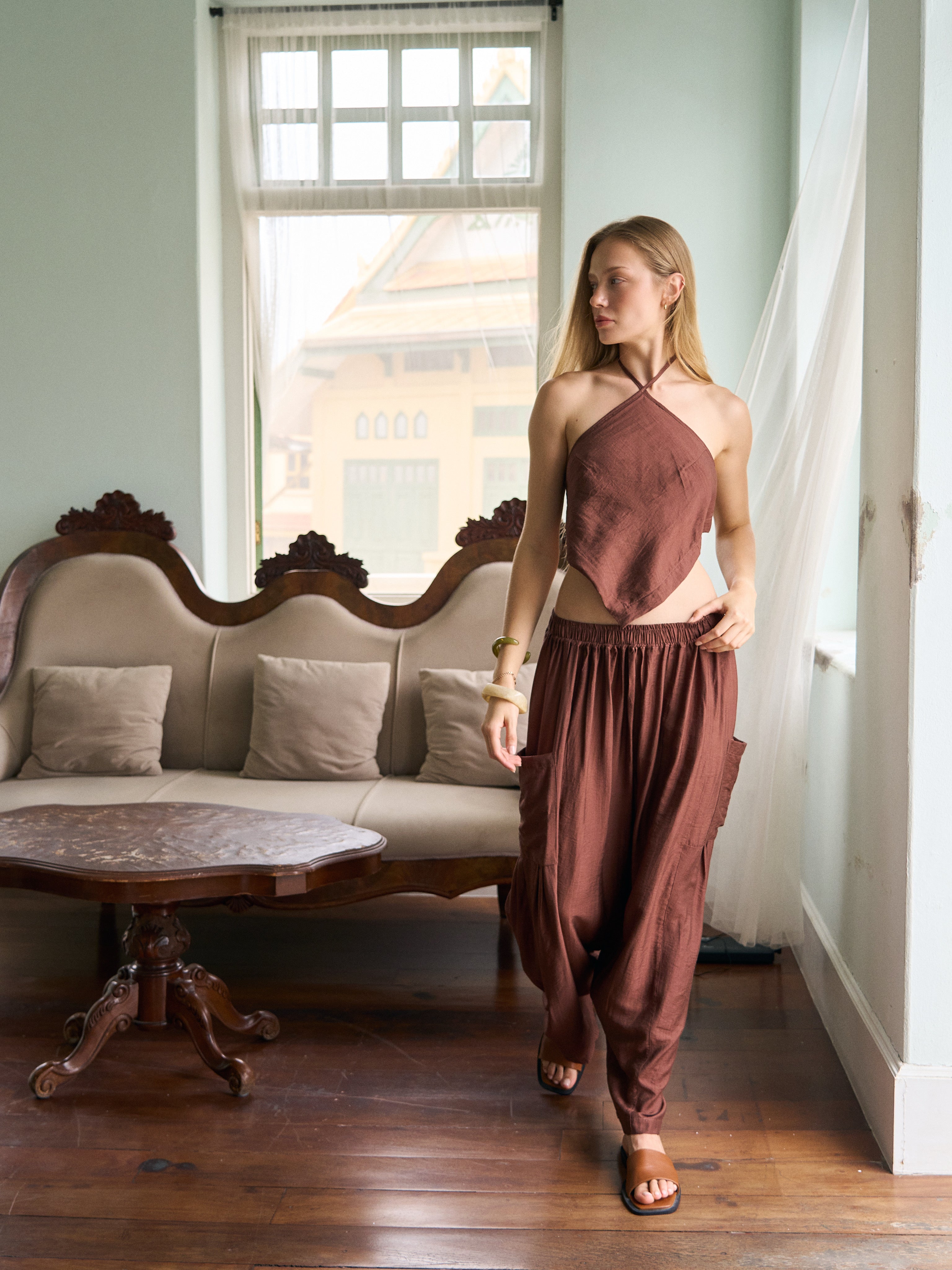 Model wearing cocoa brown wide-leg pants with a matching halter top, a chic vacation outfit perfect for festival style, beach days, and resort wear.