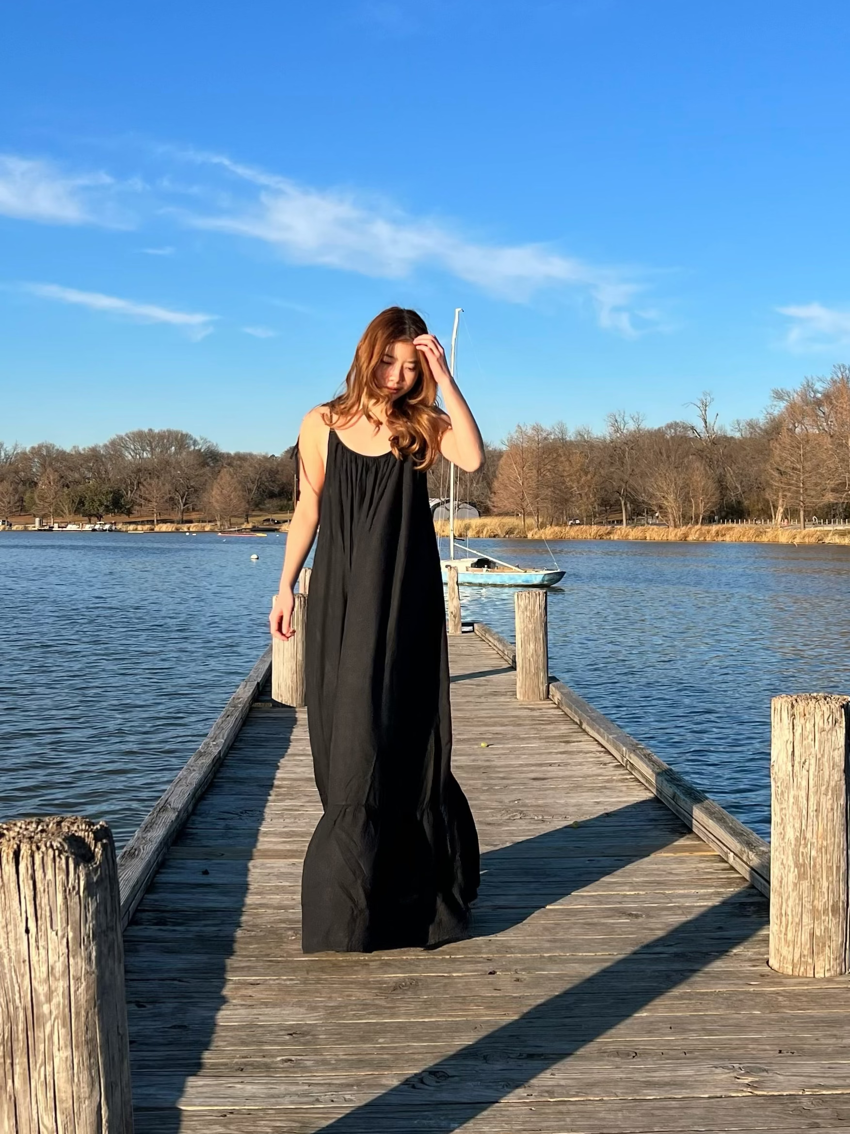 Woman in a hand-dyed black backless maxi dress standing by the sea, wearing boho resortwear by Coco de Chom