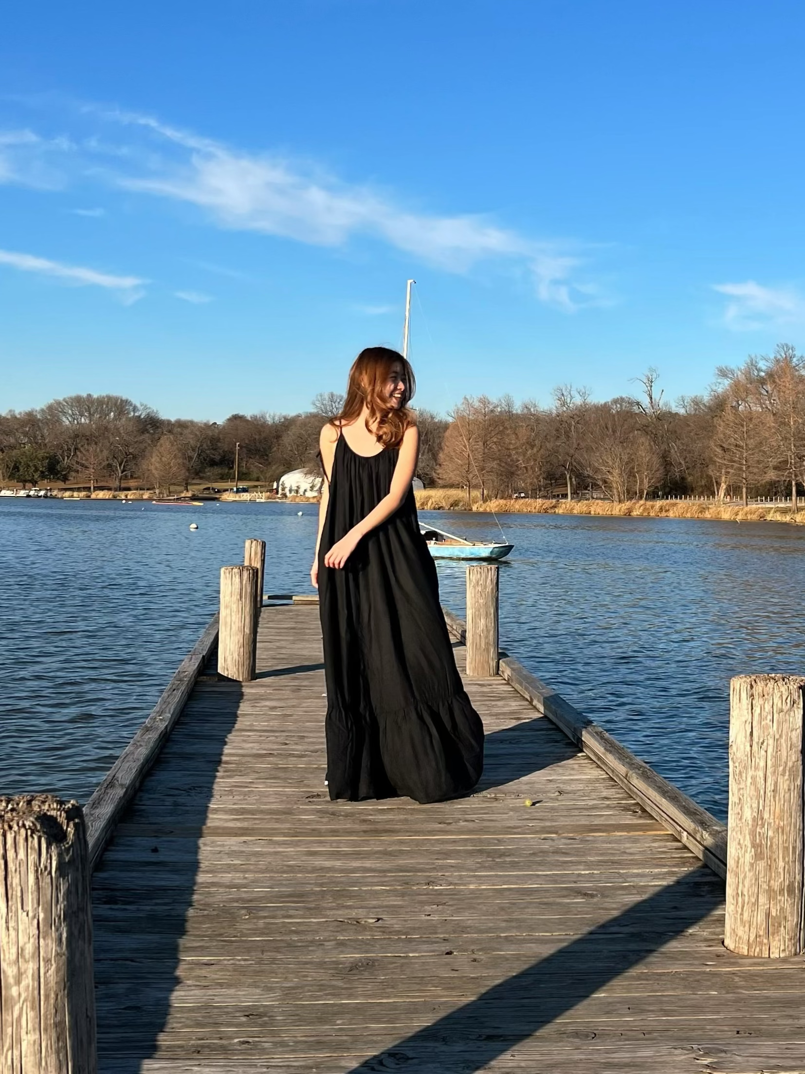 Woman in a hand-dyed black backless maxi dress standing by the sea, wearing boho resortwear by Coco de Chom