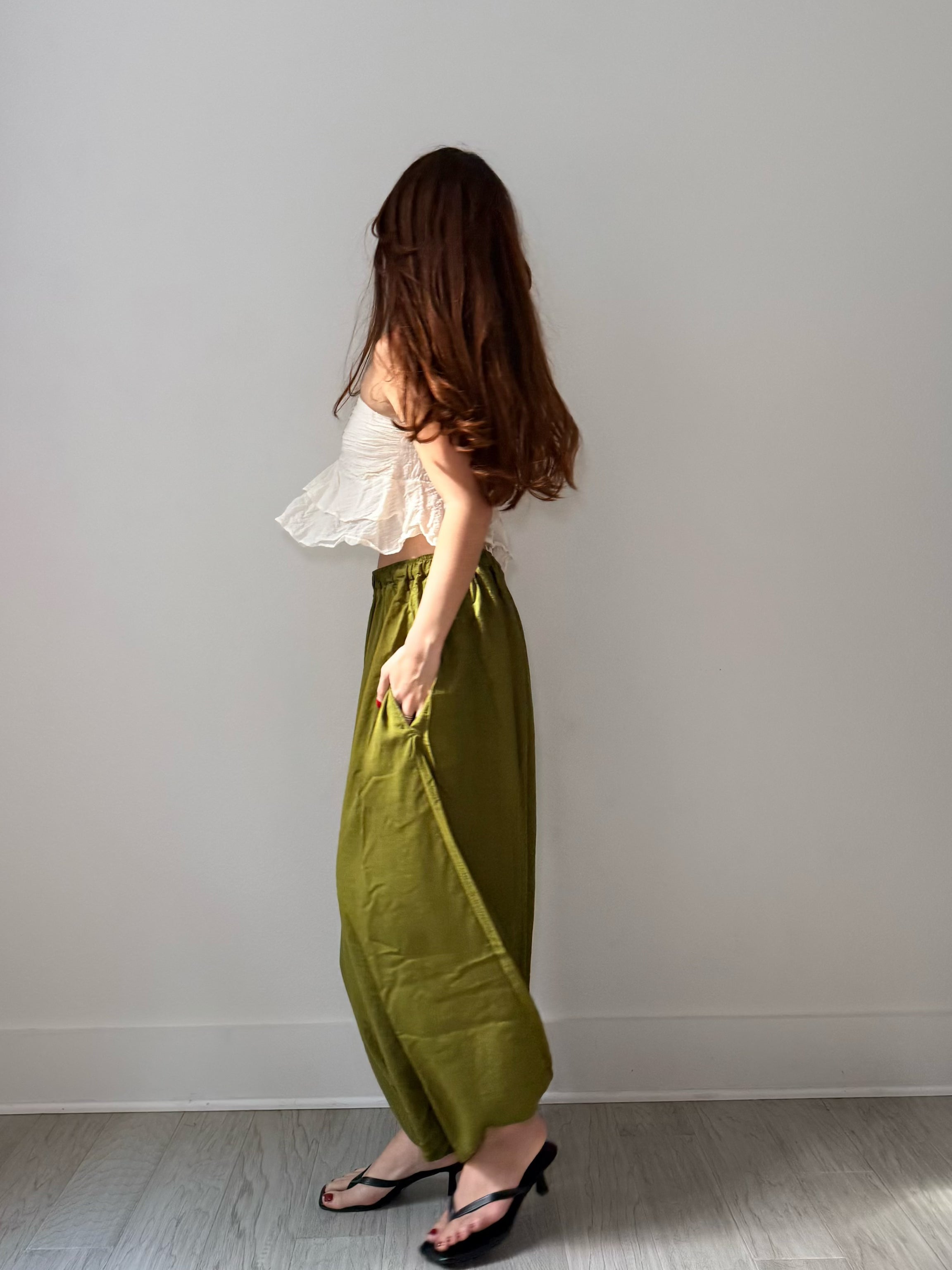 Side view of olive green harem pants showing a side pocket and relaxed balloon-leg shape