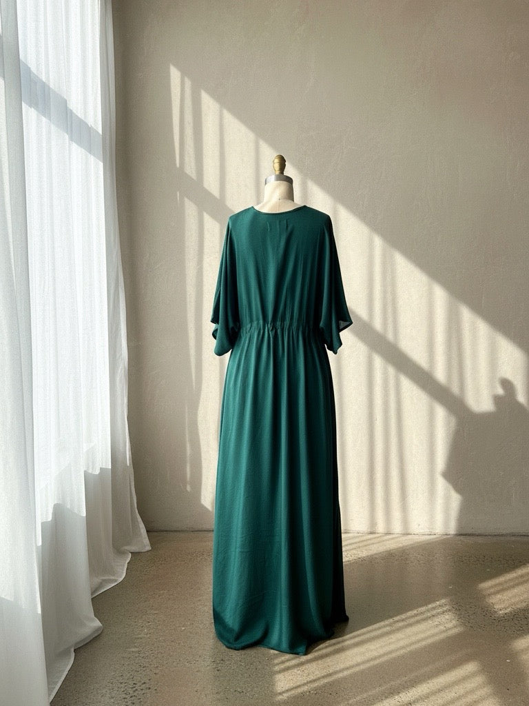 a flowy green kaftan maxi dress on the beach, featuring a deep V-neck, side slit, and cinched waist—handmade resortwear by Coco de Chom