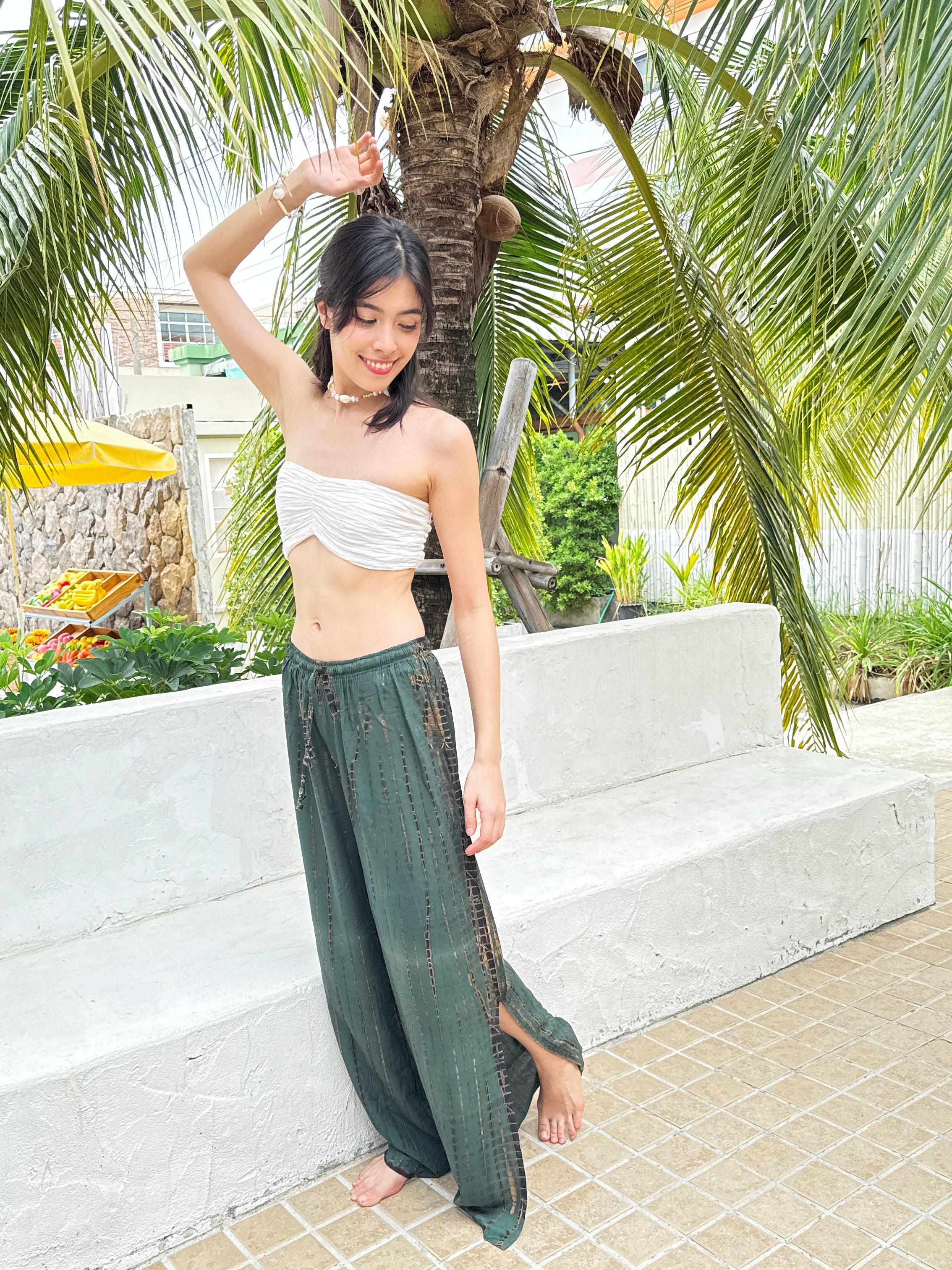 Model wearing boho tie dye pants by the beach, styled with crop top – perfect for summer vacations or festivals