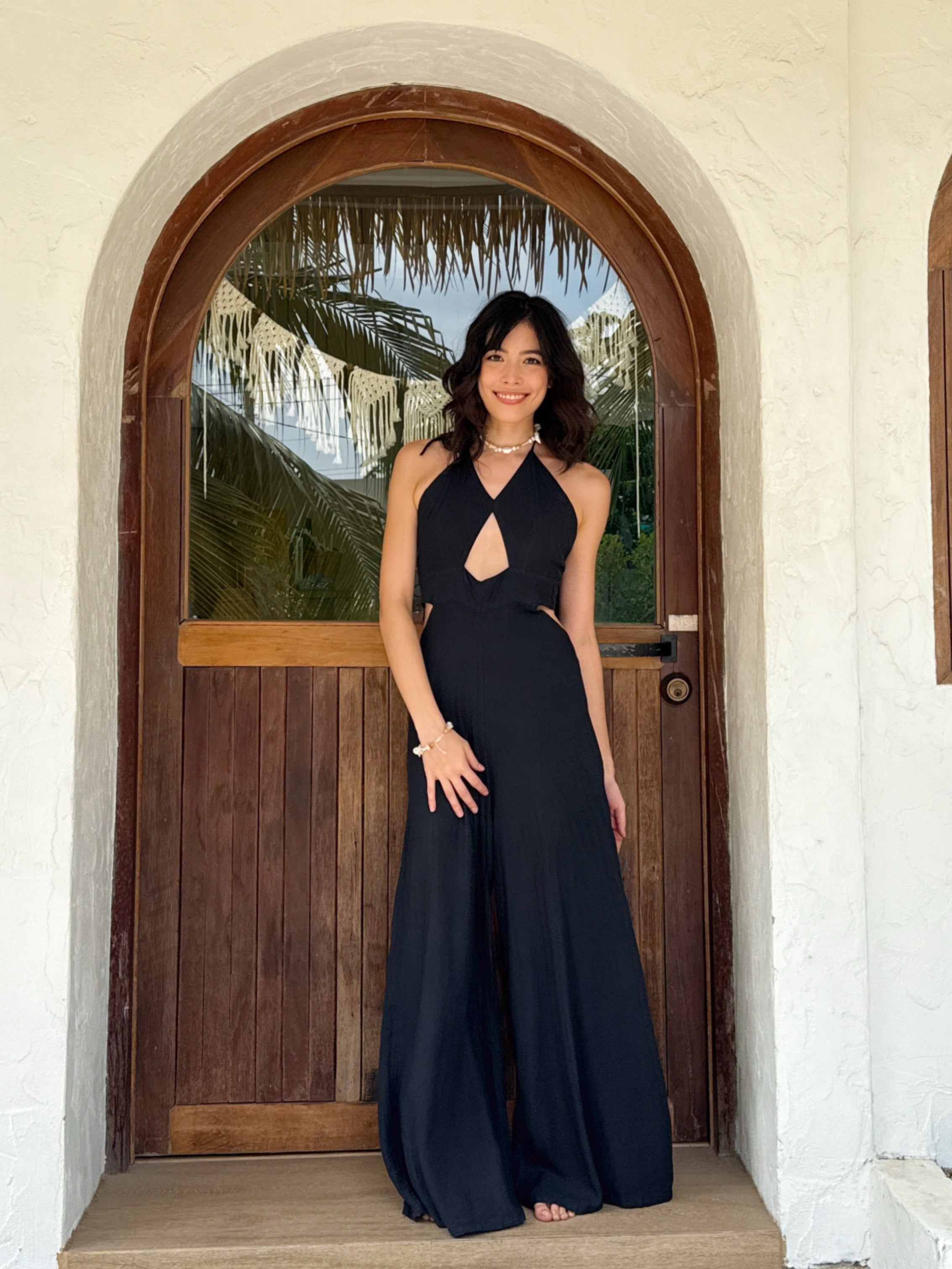 Model wearing black cut-out jumpsuit with wide legs and pockets – boho resortwear for summer beach vacation